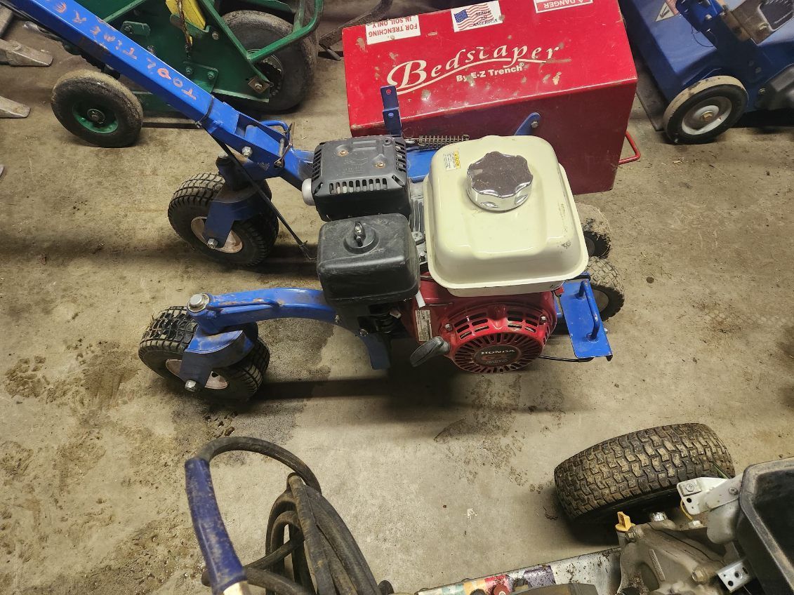 Blue minibike with a white fuel tank sits in a garage beside a red toolbox and other parts