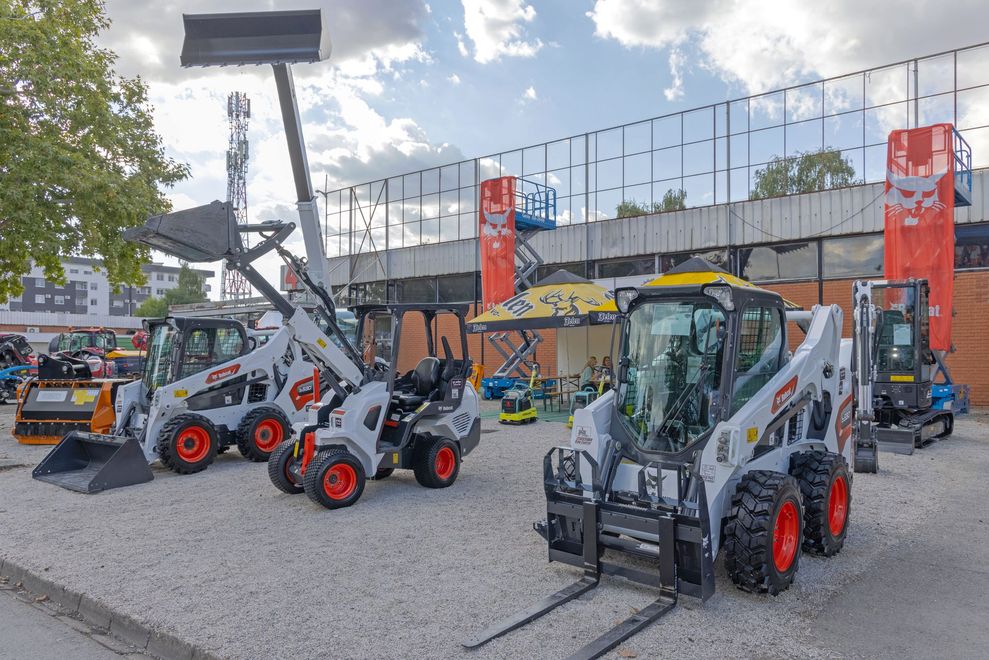 Compact loaders and excavators displayed outdoors at a construction equipment lot.