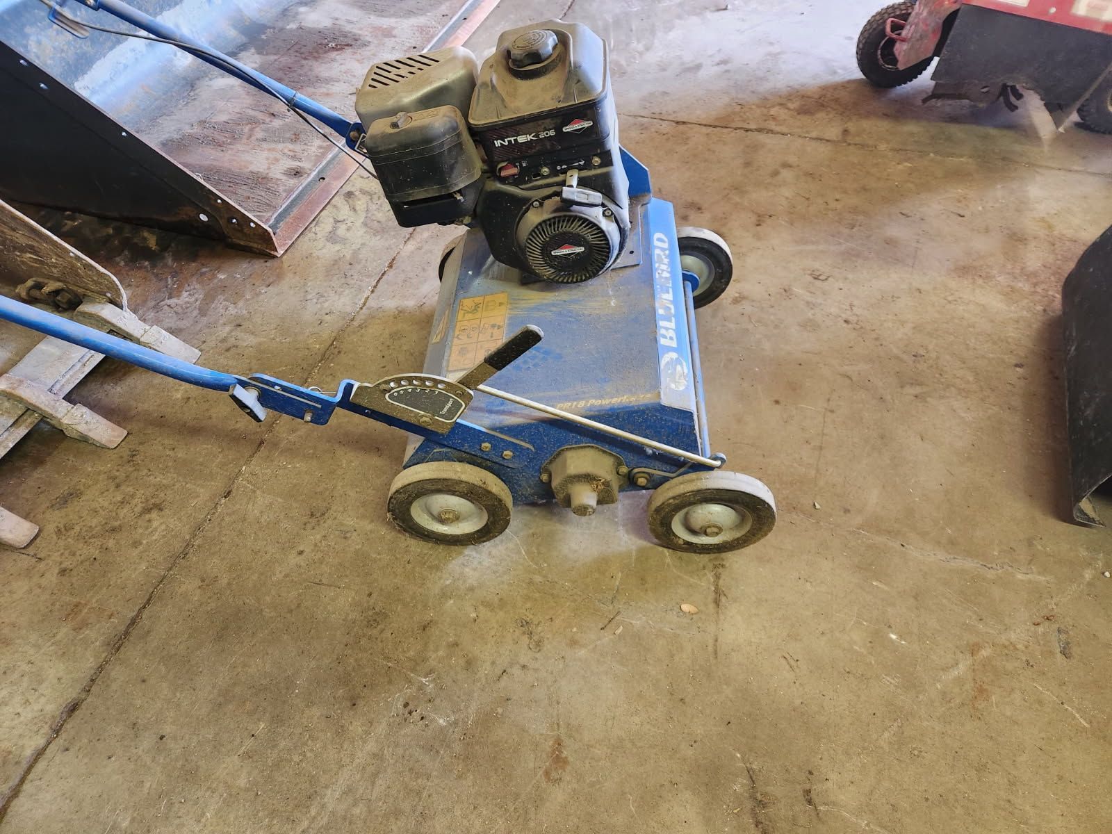 Blue hand truck with a black engine or compressor on a concrete floor in a garage