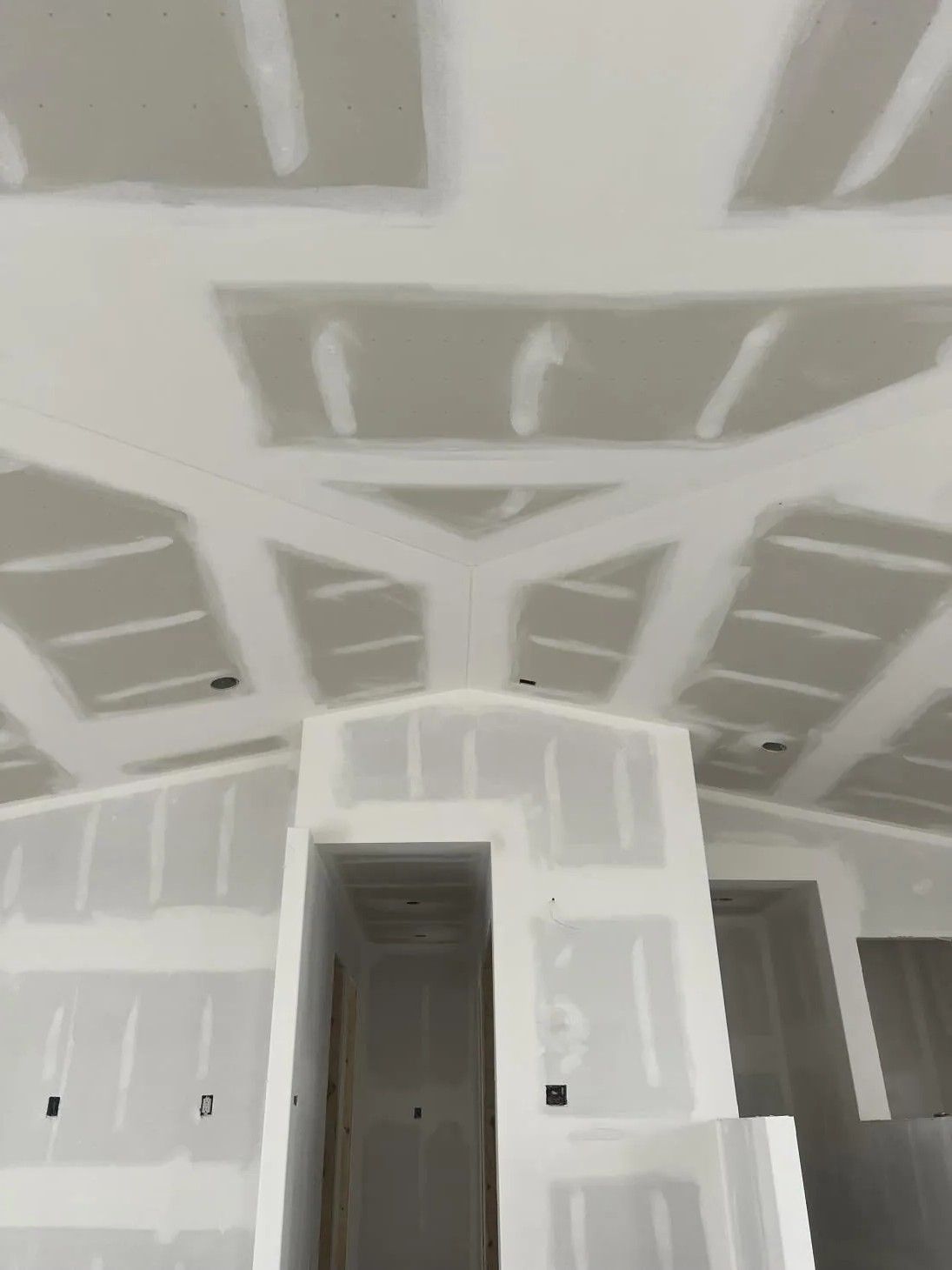 Drywall-covered ceiling and walls in a construction site.