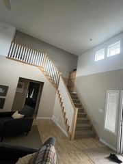 Wooden staircase with white railings in a house. Light wood floors and tan walls.