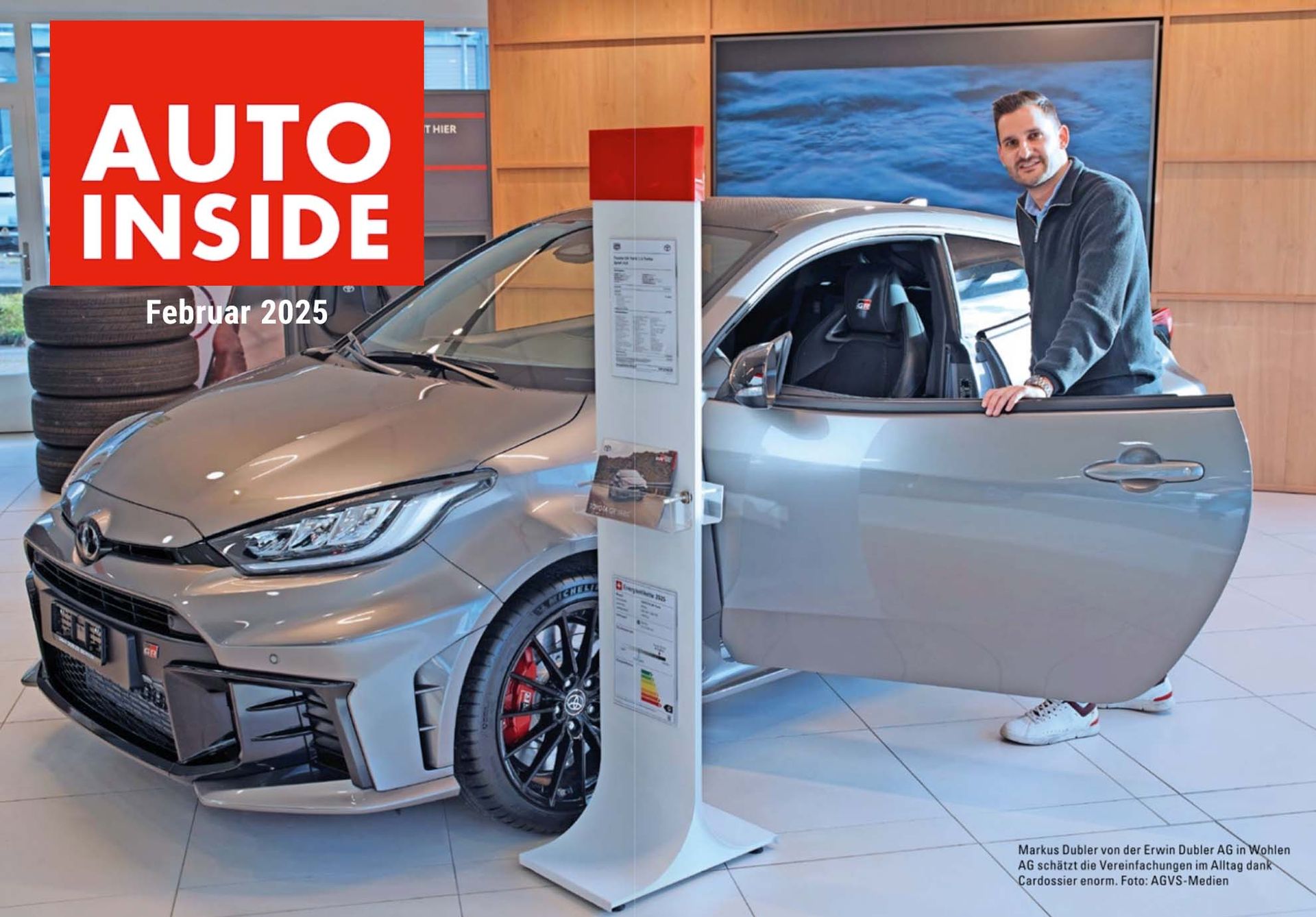 Ein Mann steht in einem Ausstellungsraum neben einem Auto.