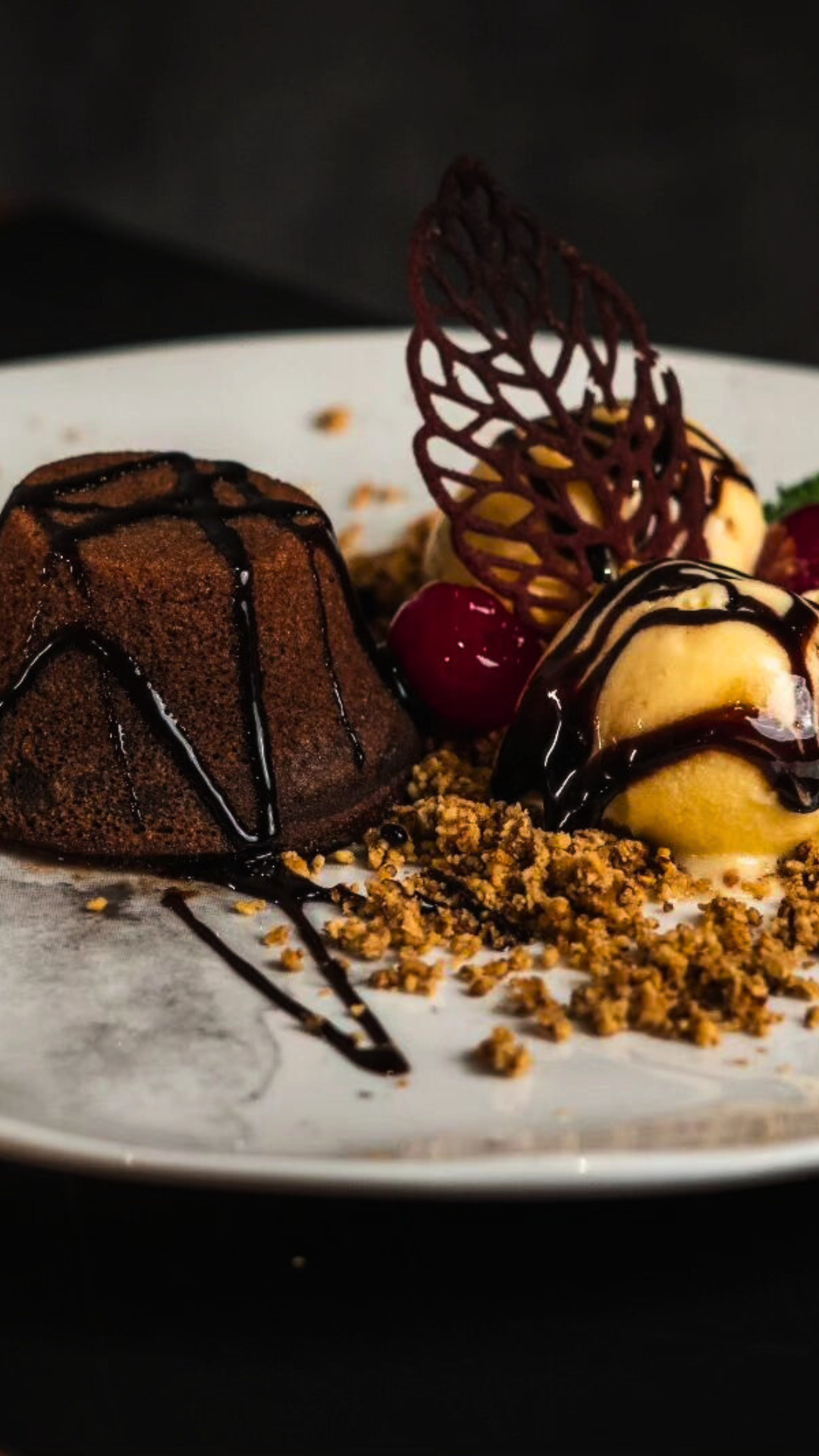 Um bolo de lava de chocolate com sorvete e frutas vermelhas em um prato branco.