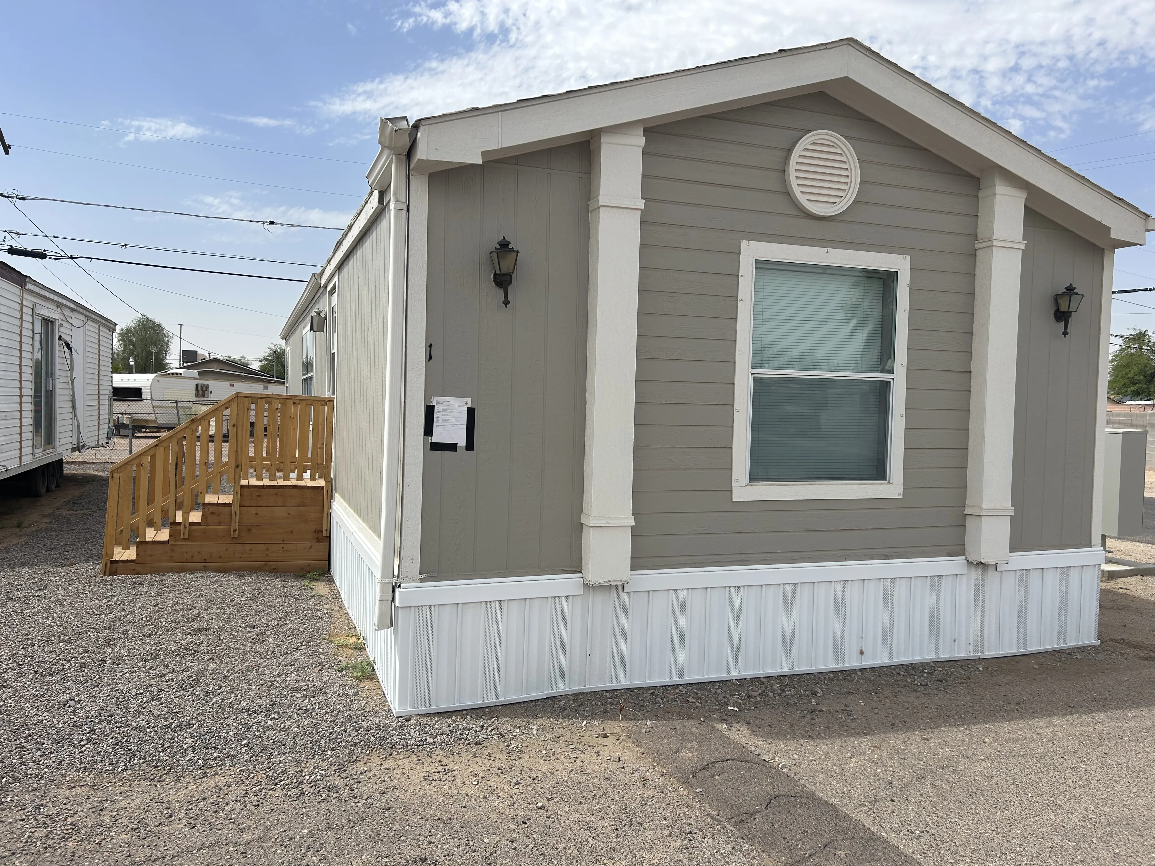 Gray manufactured home with new white skirting and wood stairs