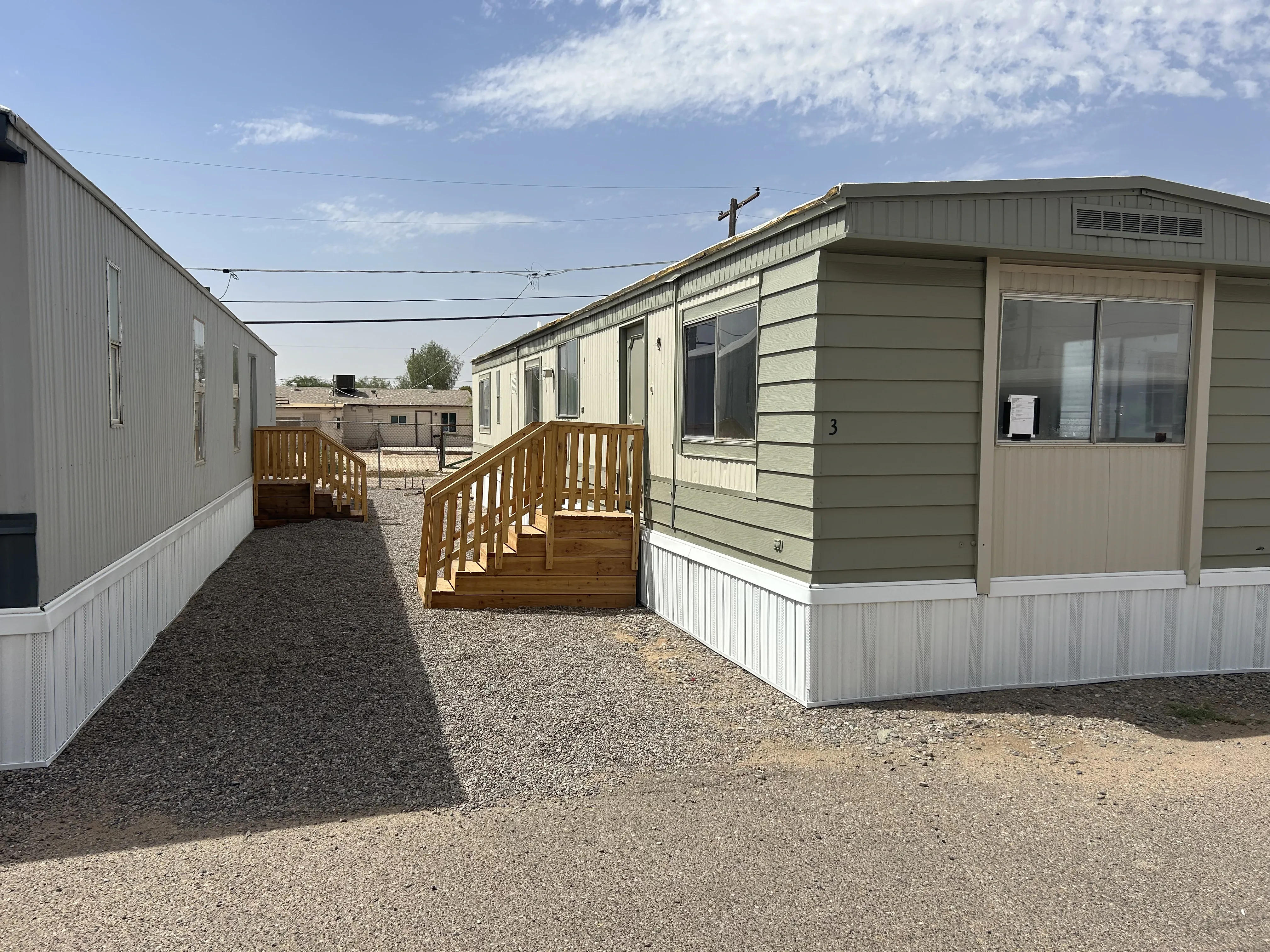 Green manufactured home with new skirting and two sets of wood stairs