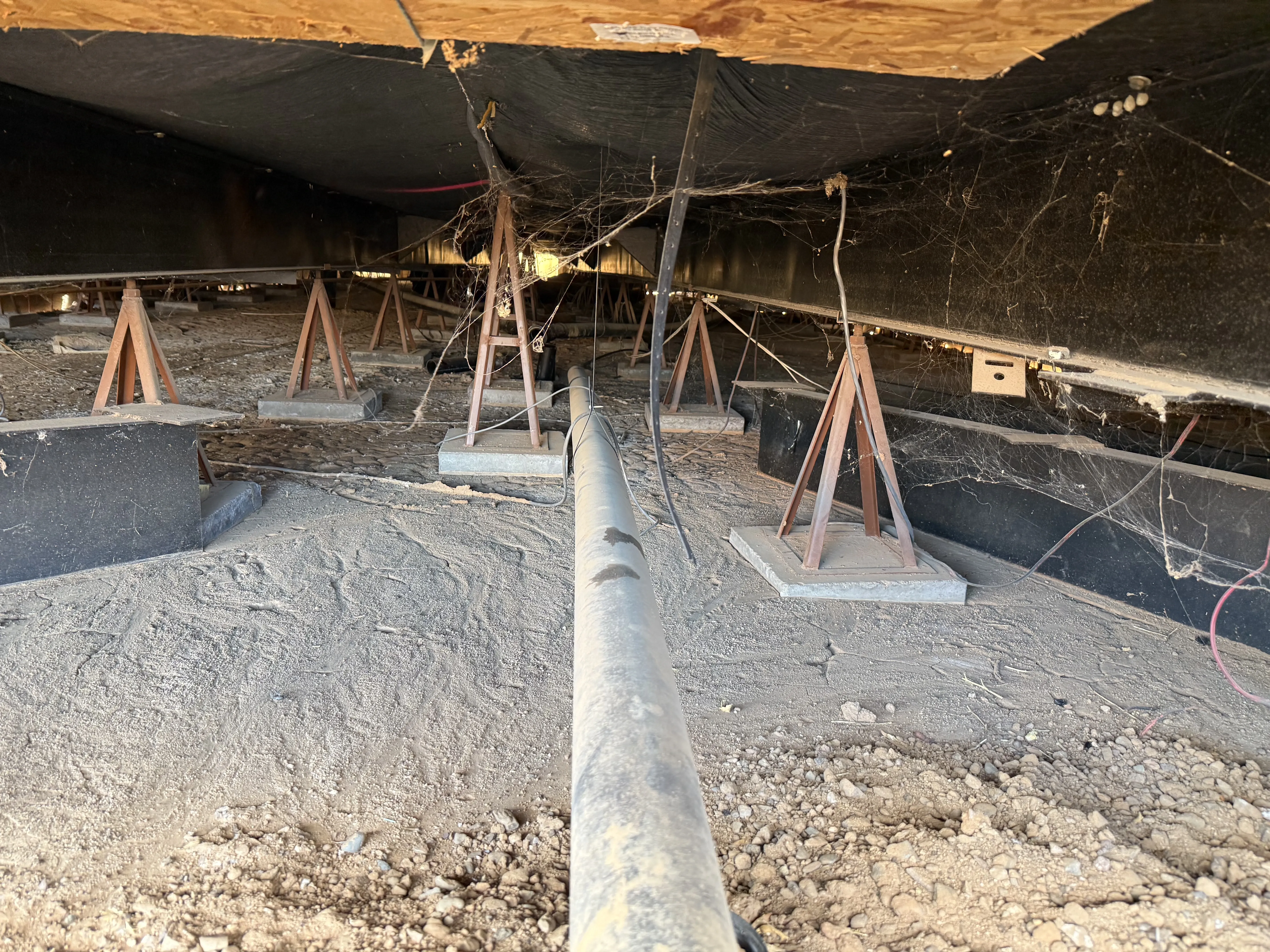 Crawl space under a mobile home with piers and jack stands