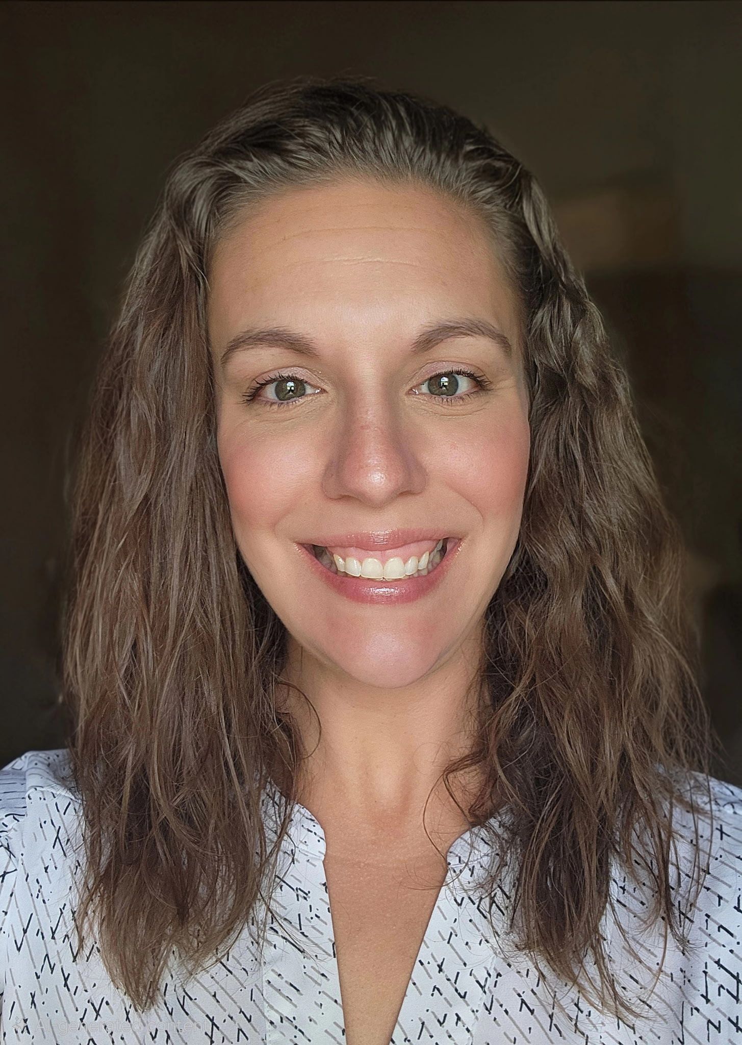 Smiling woman with long brown hair against a dark background, wearing a light patterned top
