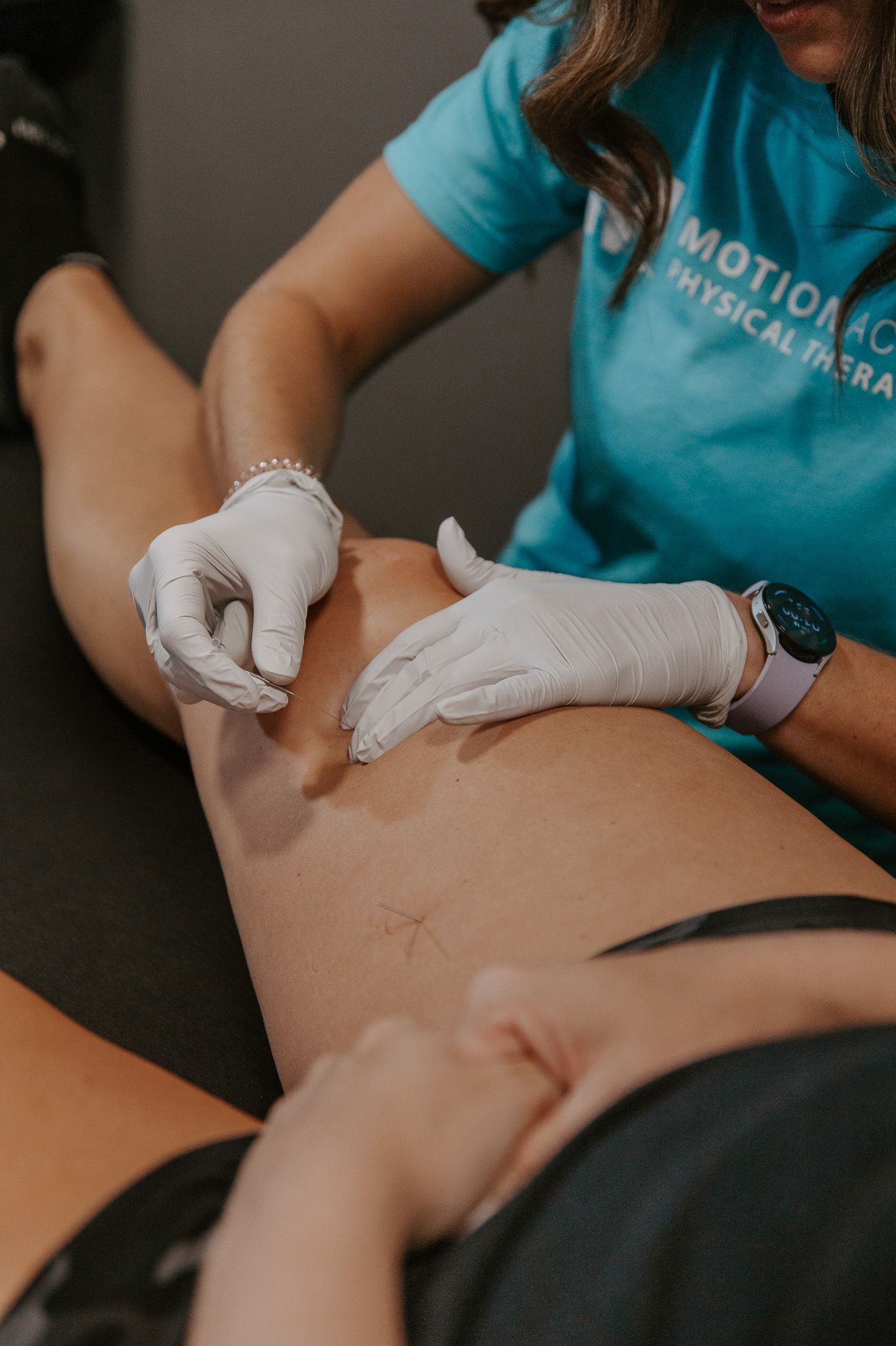 Gloved therapist massaging a patient’s leg in a clinical setting
