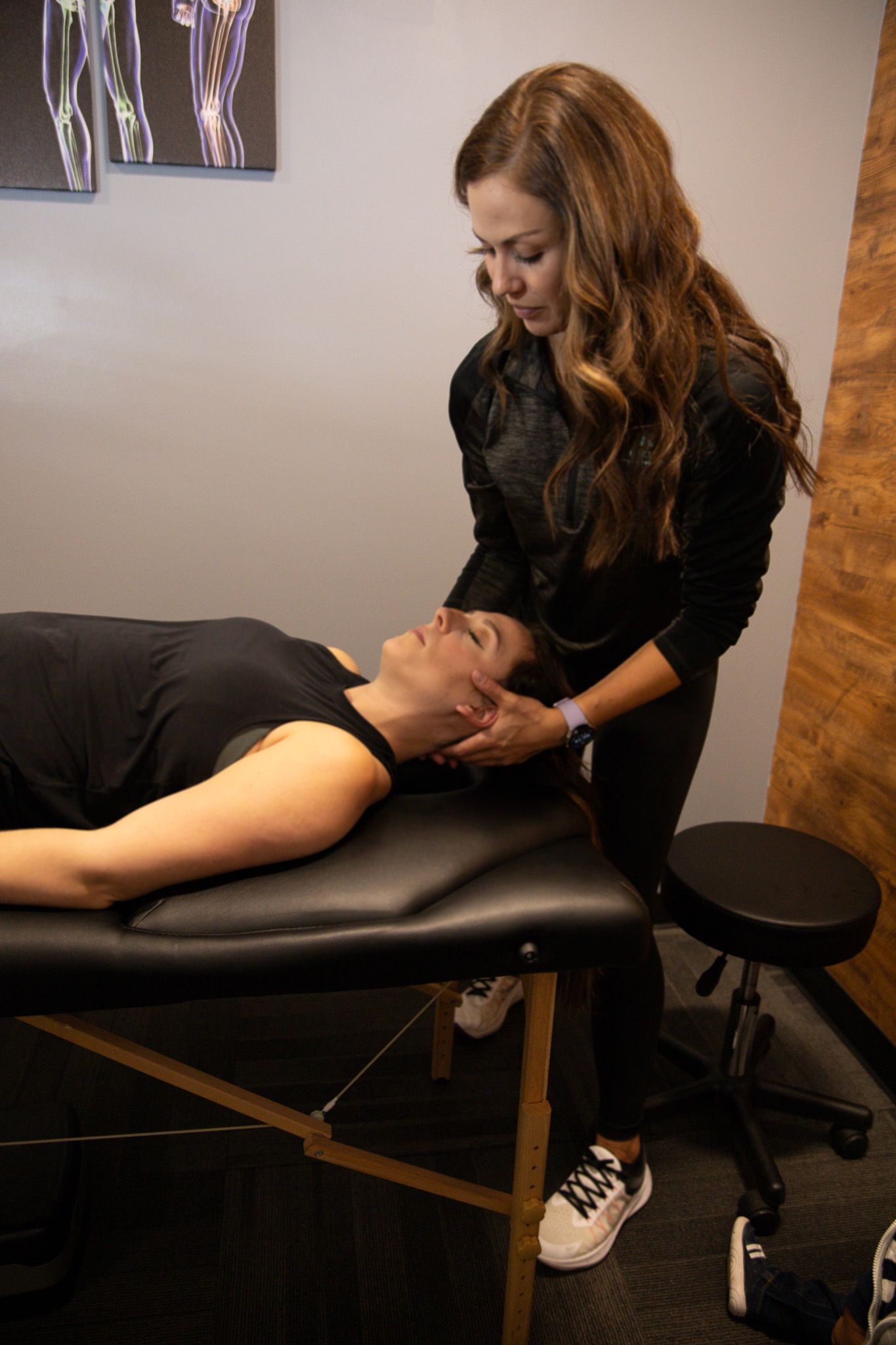 Massage therapist working on a client’s neck on a treatment table in a clinic room