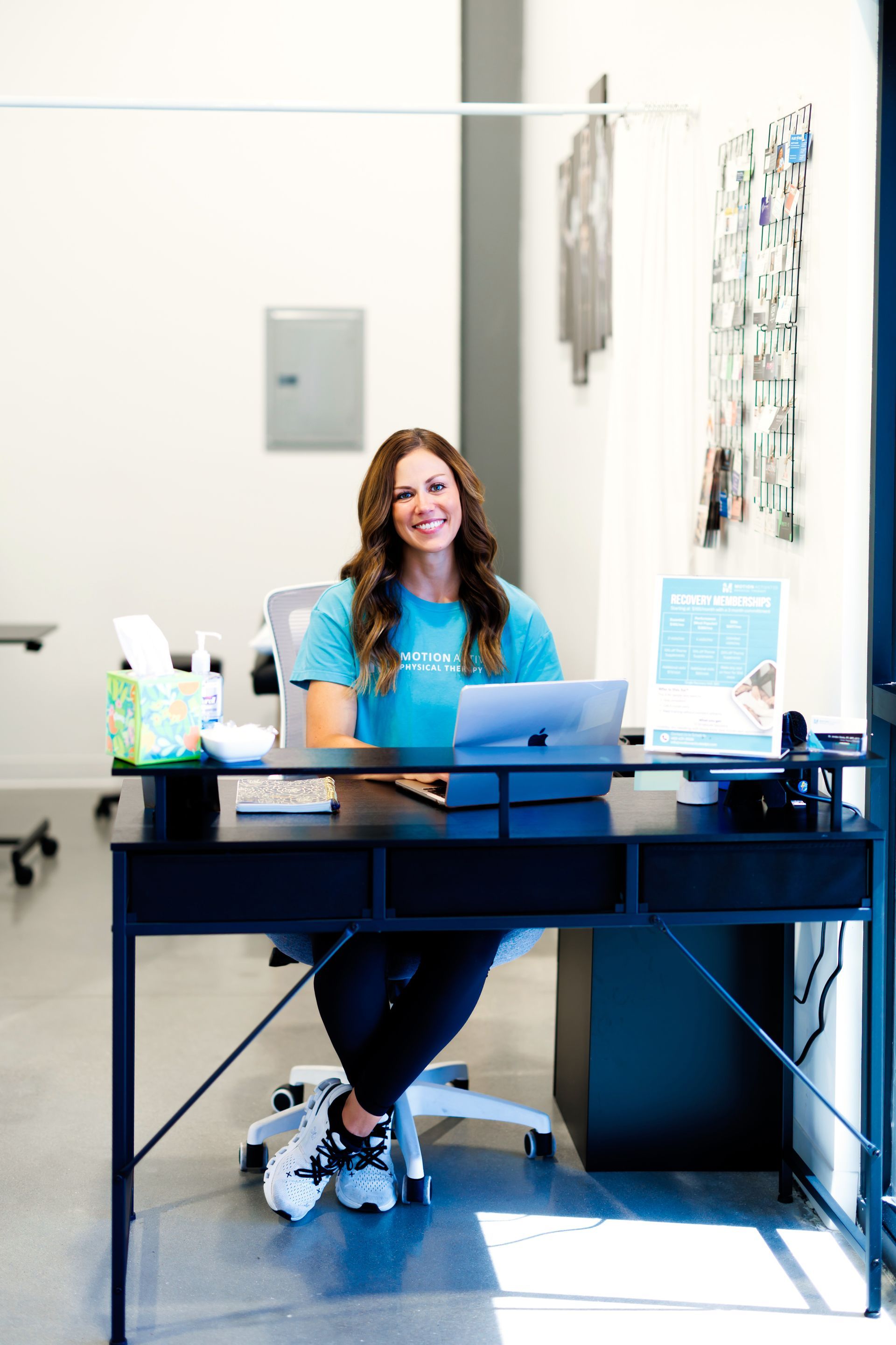 Woman sitting at a desk with a laptop in a bright office lobby