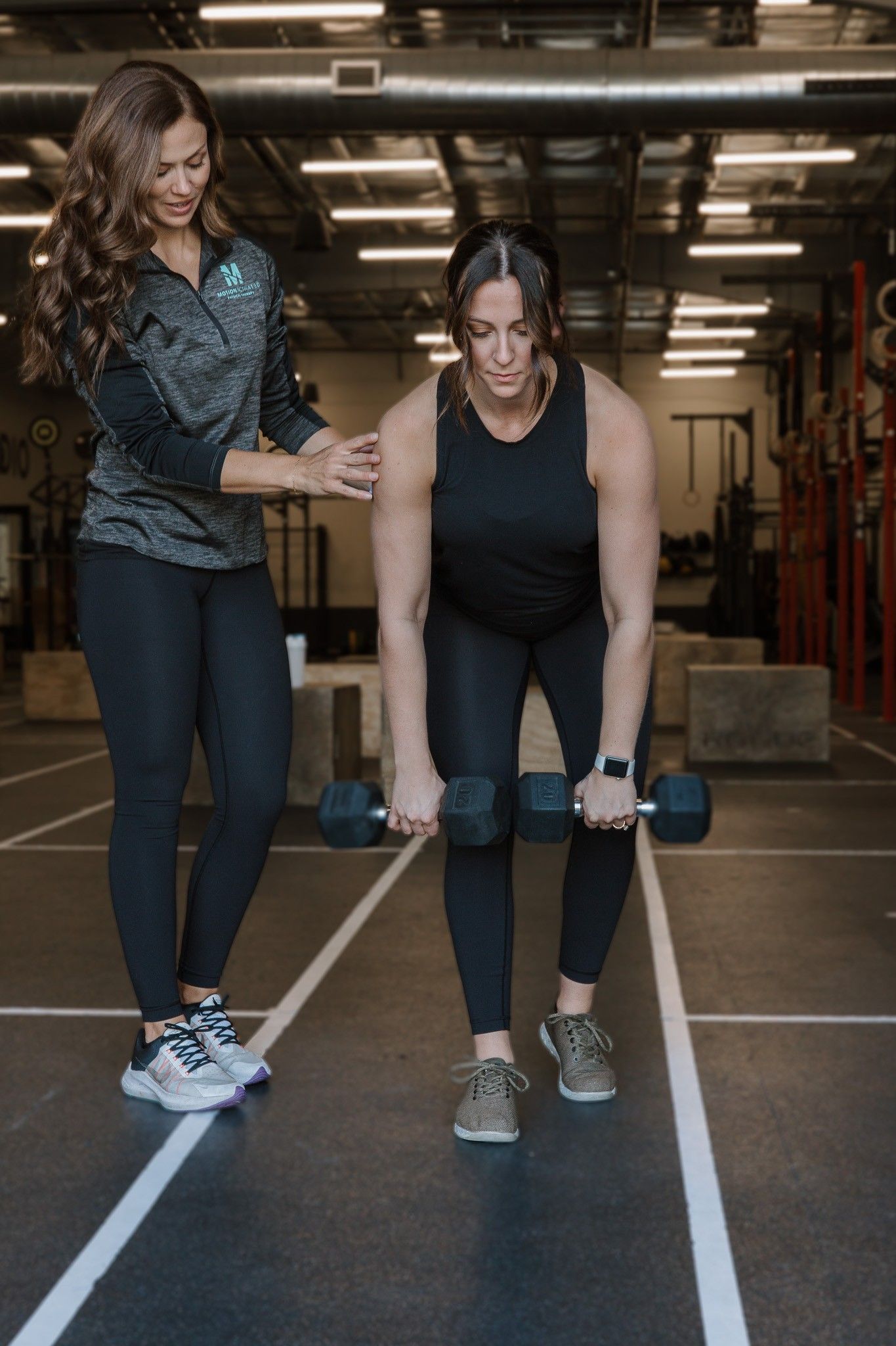 Two people seated on a gym floor using a resistance band in an indoor fitness space