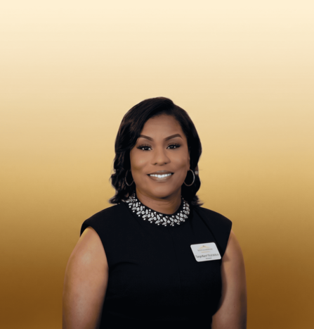 Portrait of a smiling woman in a black dress with a jeweled collar against a gold background