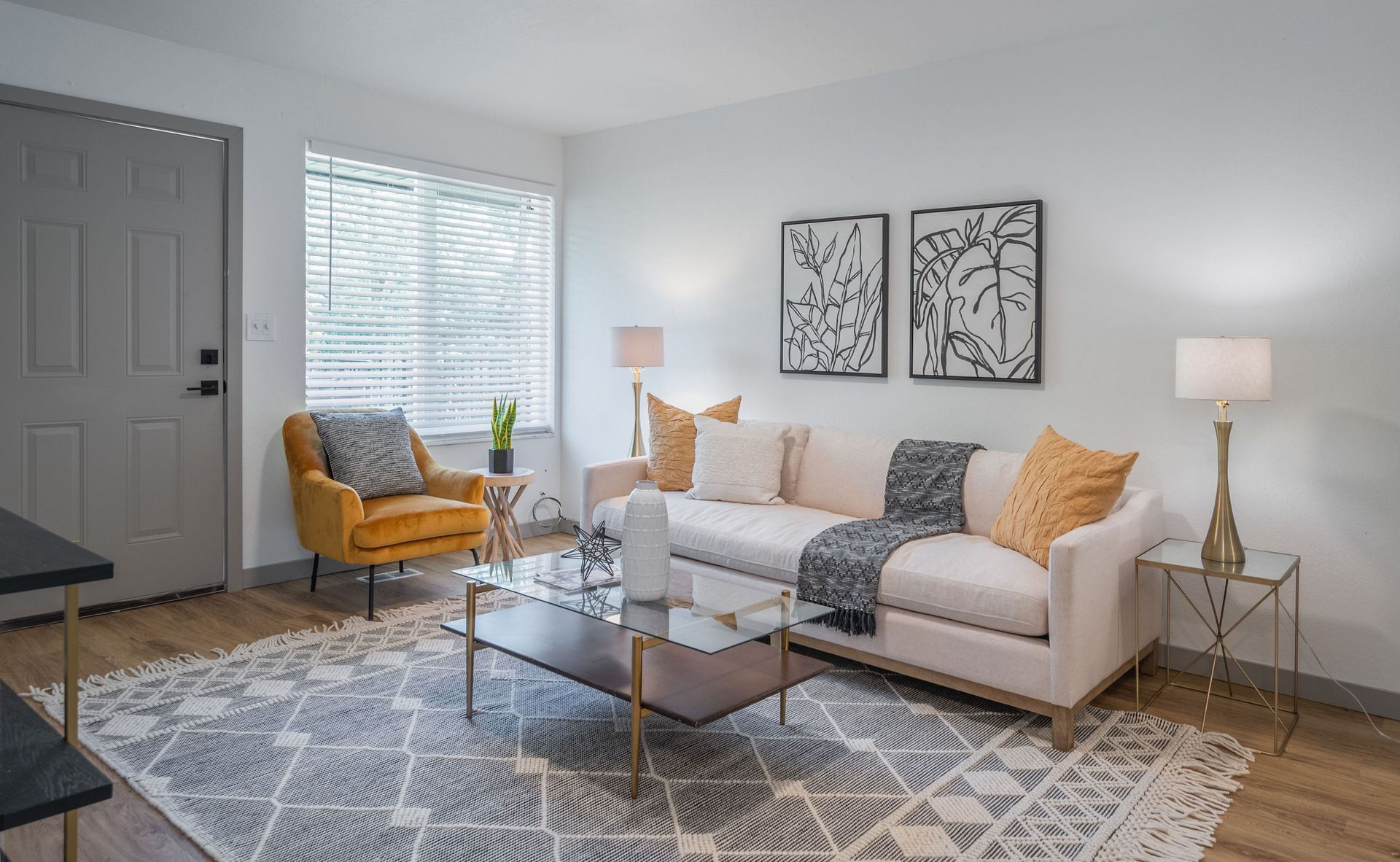 Living room with sofa, armchair, coffee table, lamps, and decorative art.