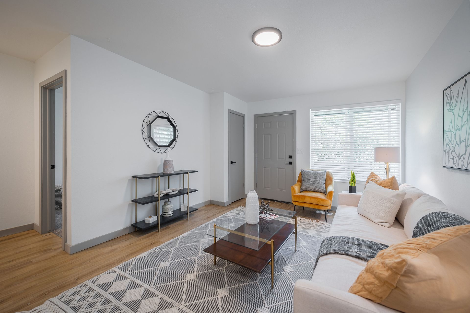 Modern living room with white walls, gray rug, and beige sofa.