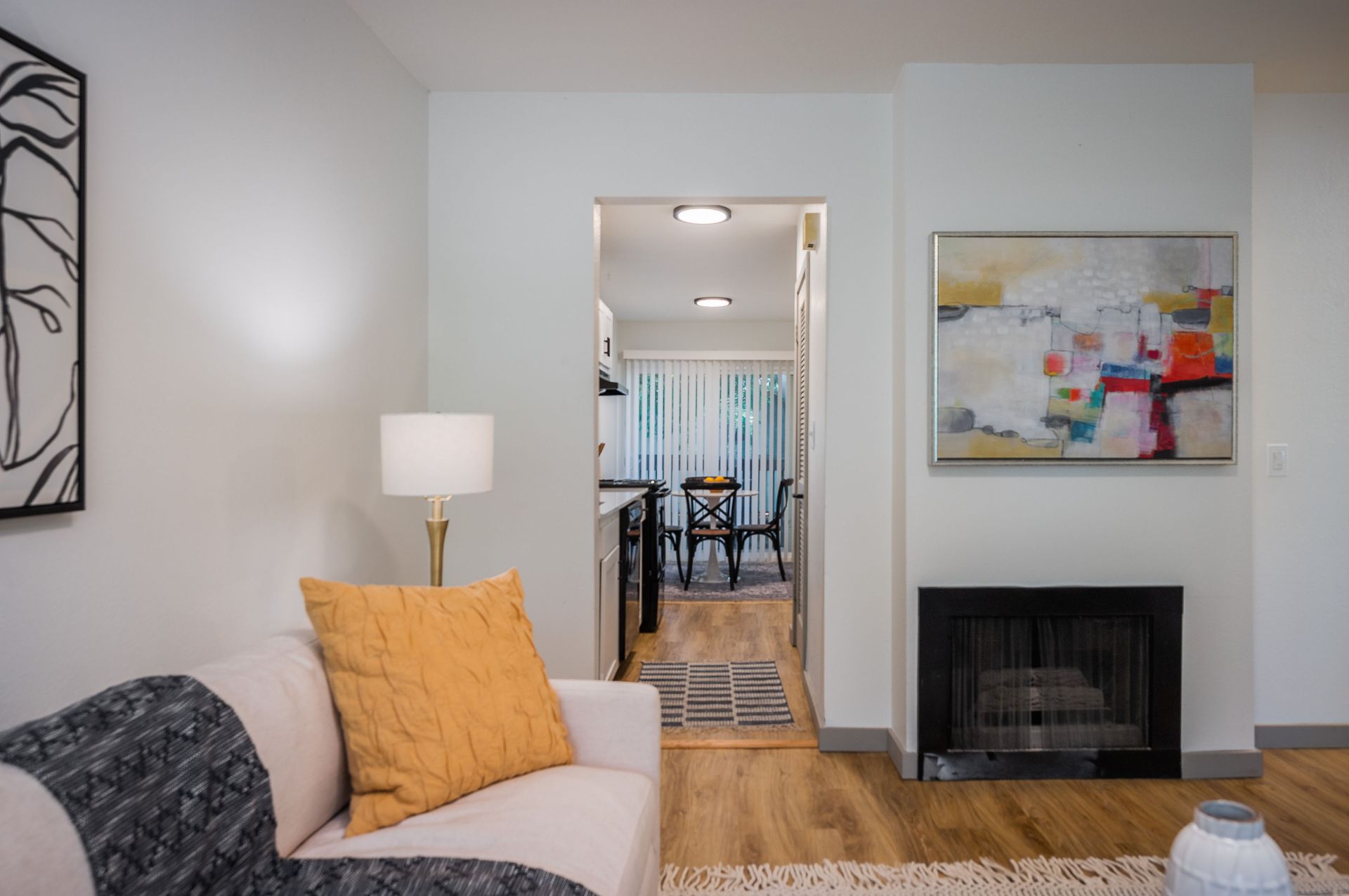 Cozy living room with a fireplace, open doorway to the kitchen, and modern art.