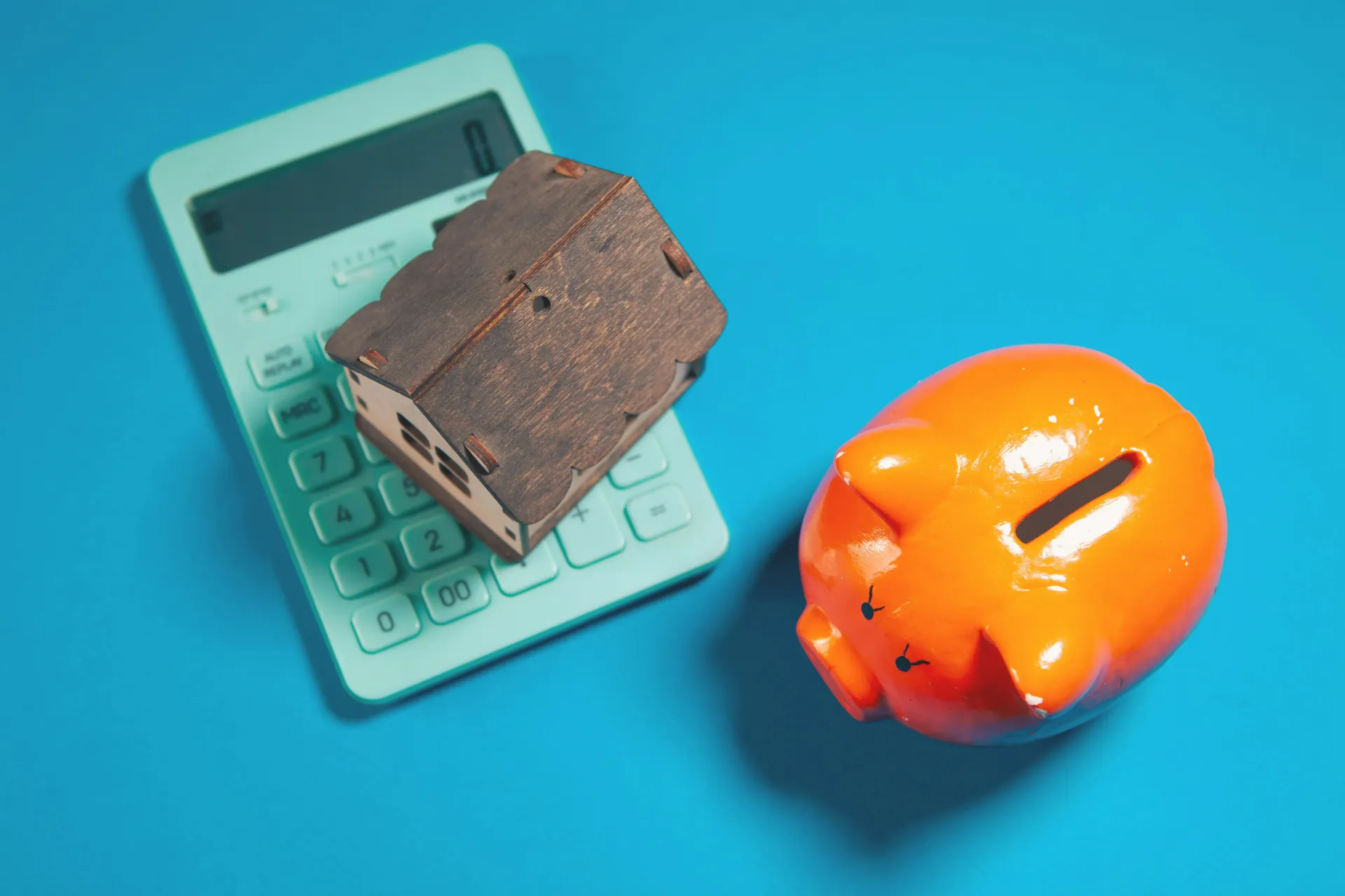 Calculator with a chocolate bar and an orange piggy bank on a blue background