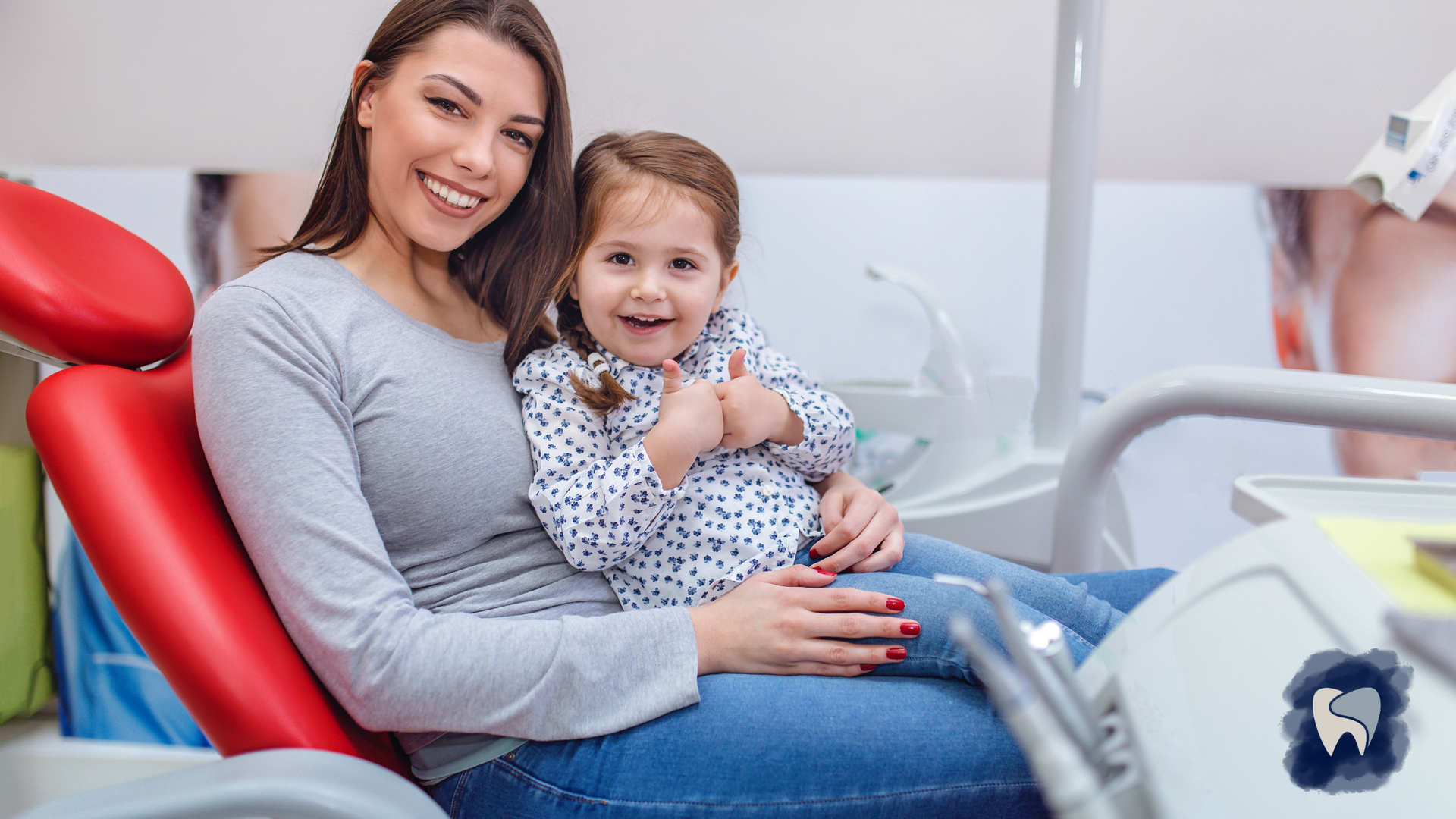 Woman and child in dental chair, smiling and giving thumbs up.