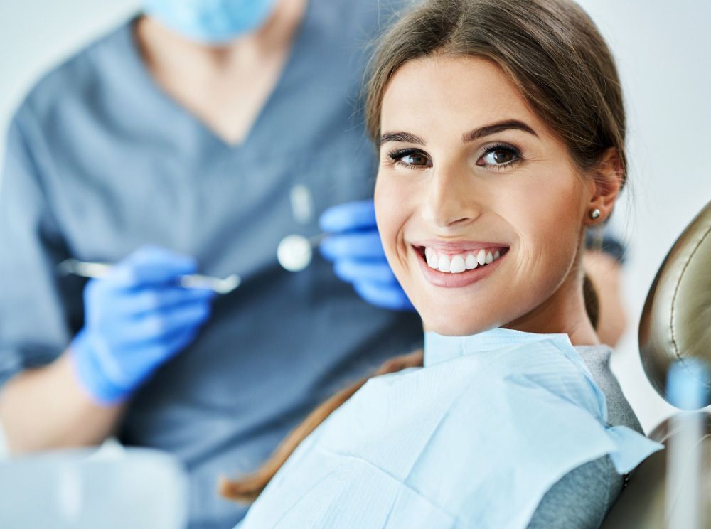 Woman at dentist, smile. Dentist holding shade guide to compare tooth color.