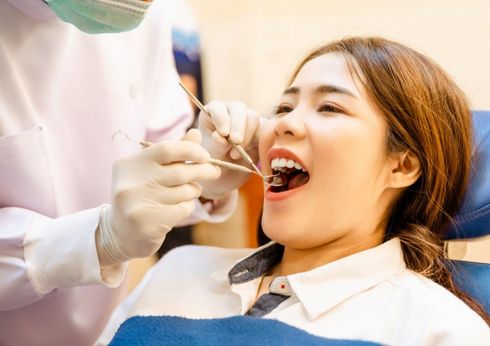 Young boy smiles at a dentist wearing a mask and examining him. Dental clinic setting.