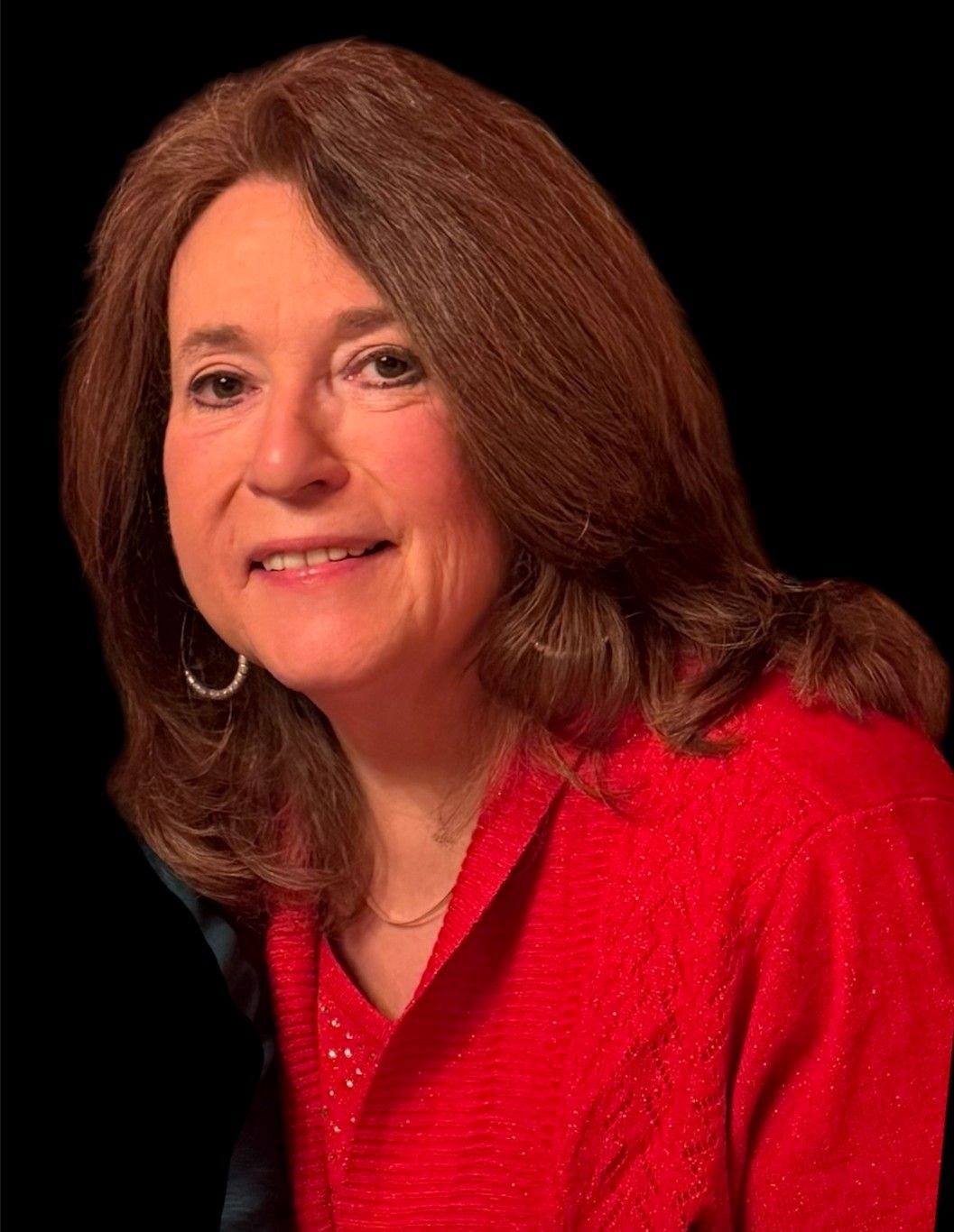 A woman wearing glasses and a pink shirt is looking at the camera.