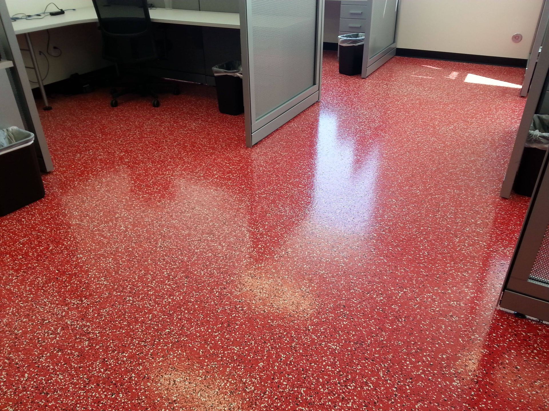 Red speckled epoxy floor in an office hallway with open cubicles and cabinets