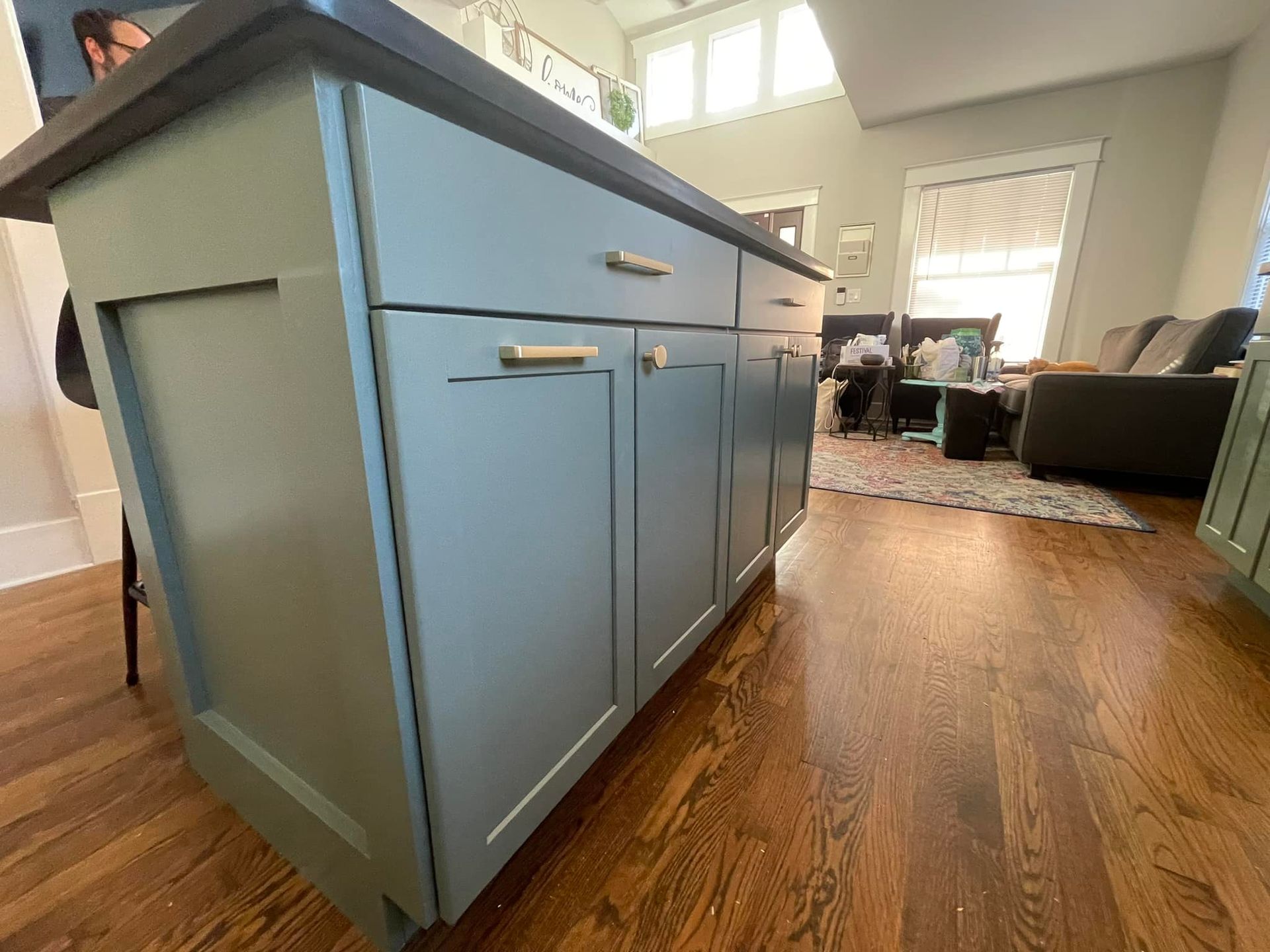 Green kitchen island with gold hardware in a home with wood floors.
