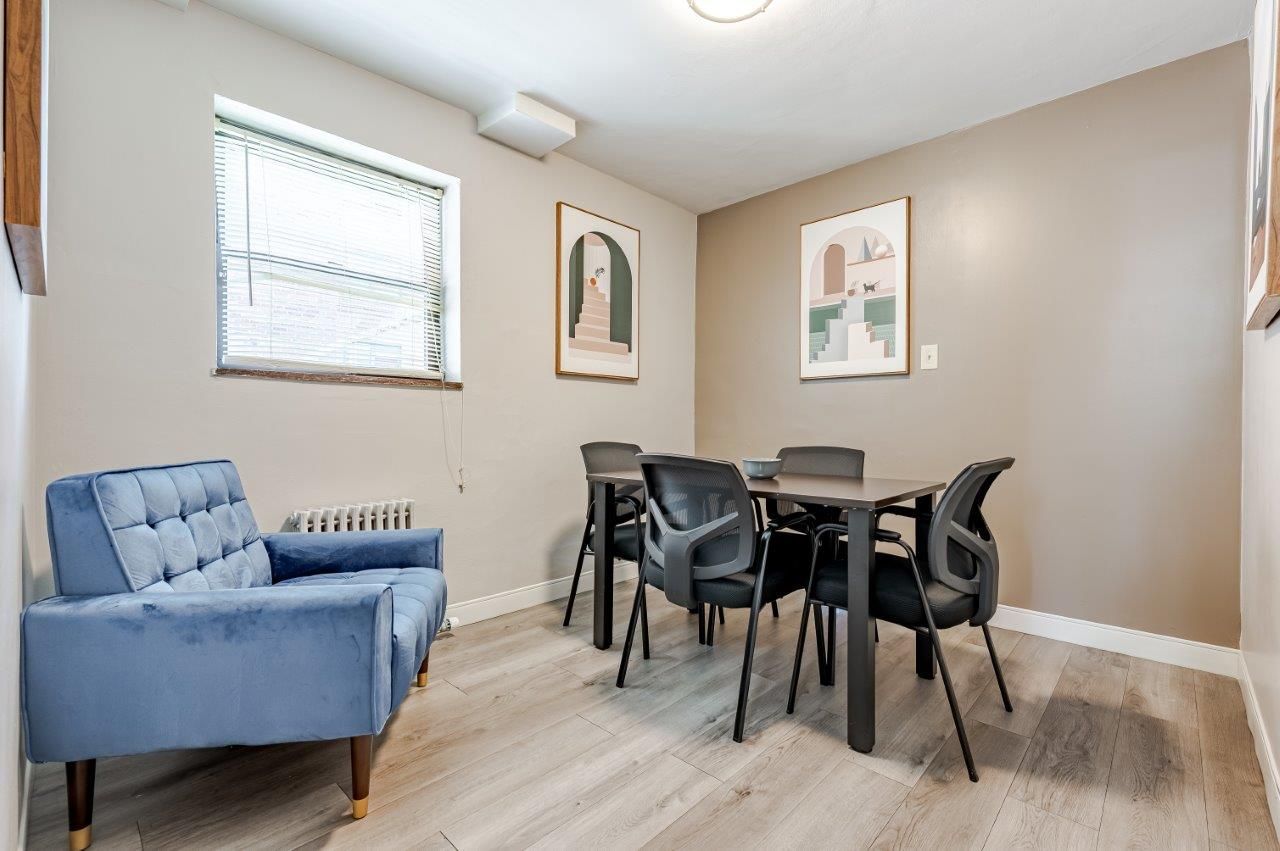Small resident lounge with a black table and chairs, blue armchair, and framed wall art.