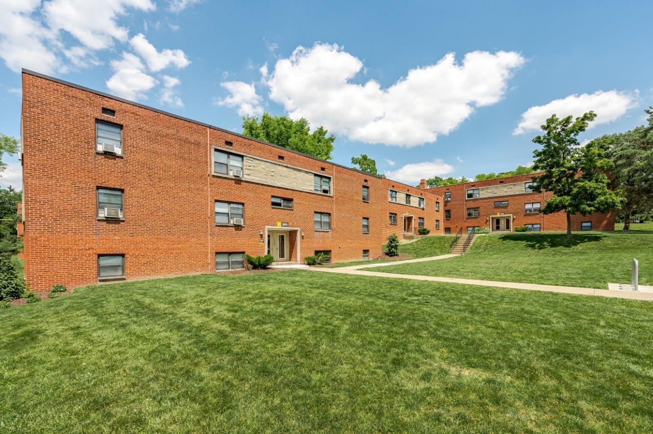 Brick apartment buildings beside a large grassy courtyard under a blue sky