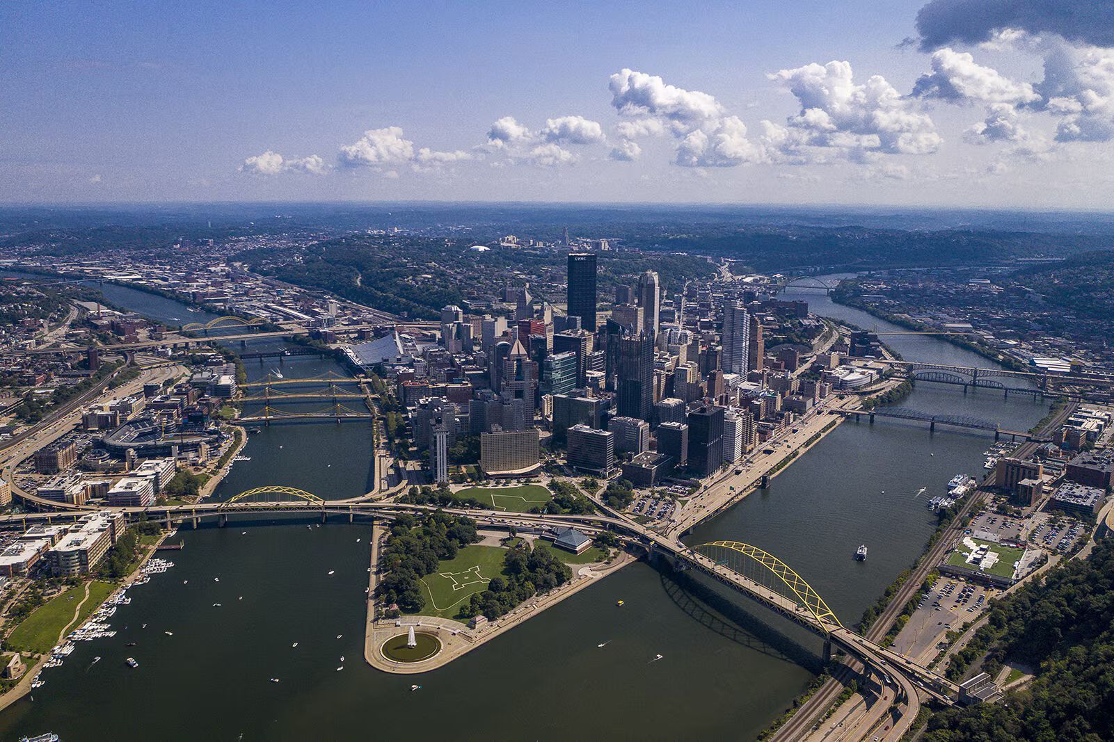 Aerial view of Pittsburgh, PA, downtown skyline surrounded by rivers and bridges on a sunny day.