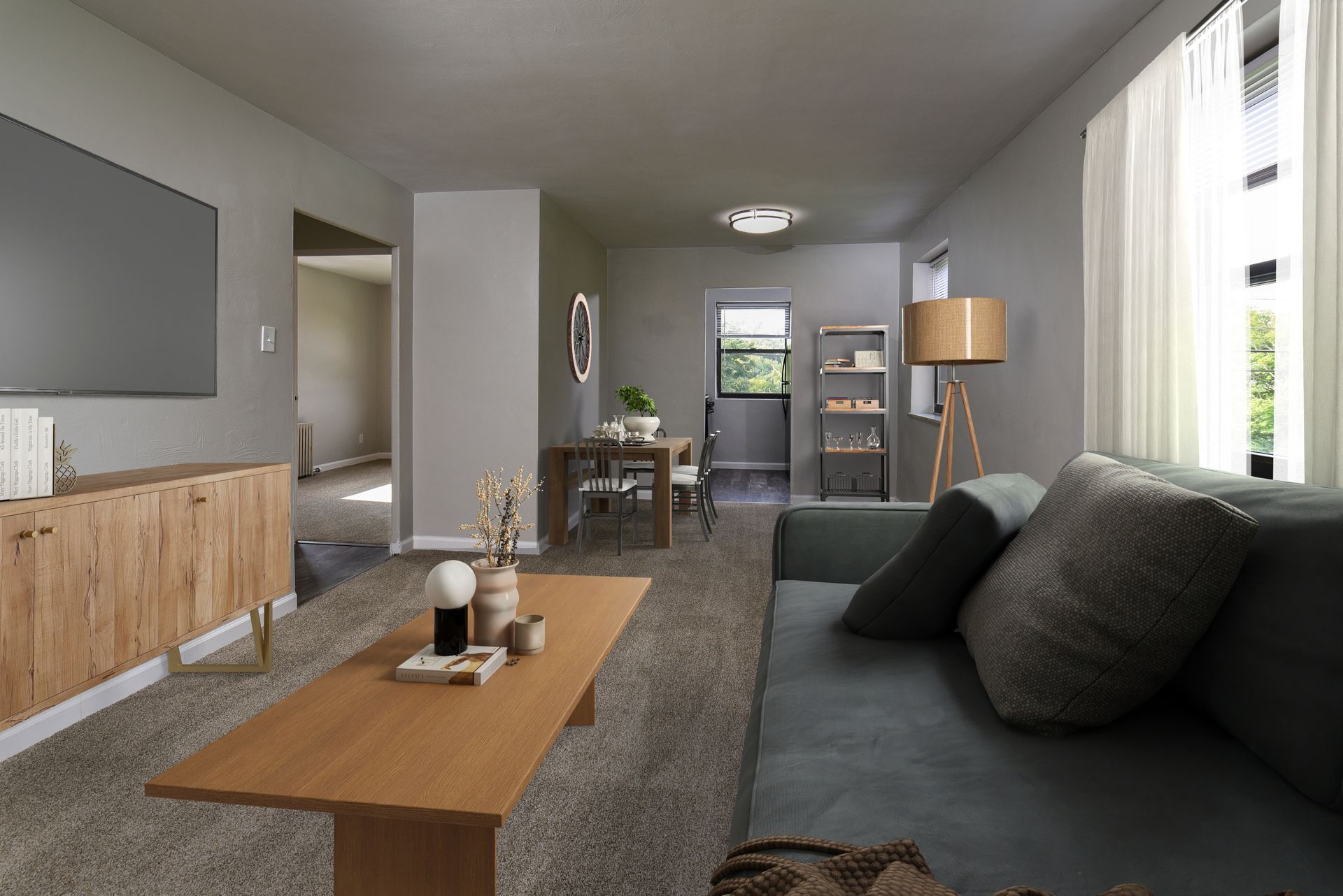 Living room with couch, coffee table, and TV on a wooden cabinet, next to a dining area.