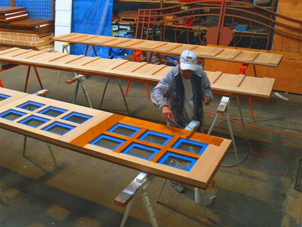 Worker painting blue window frames on a workbench in a workshop or factory
