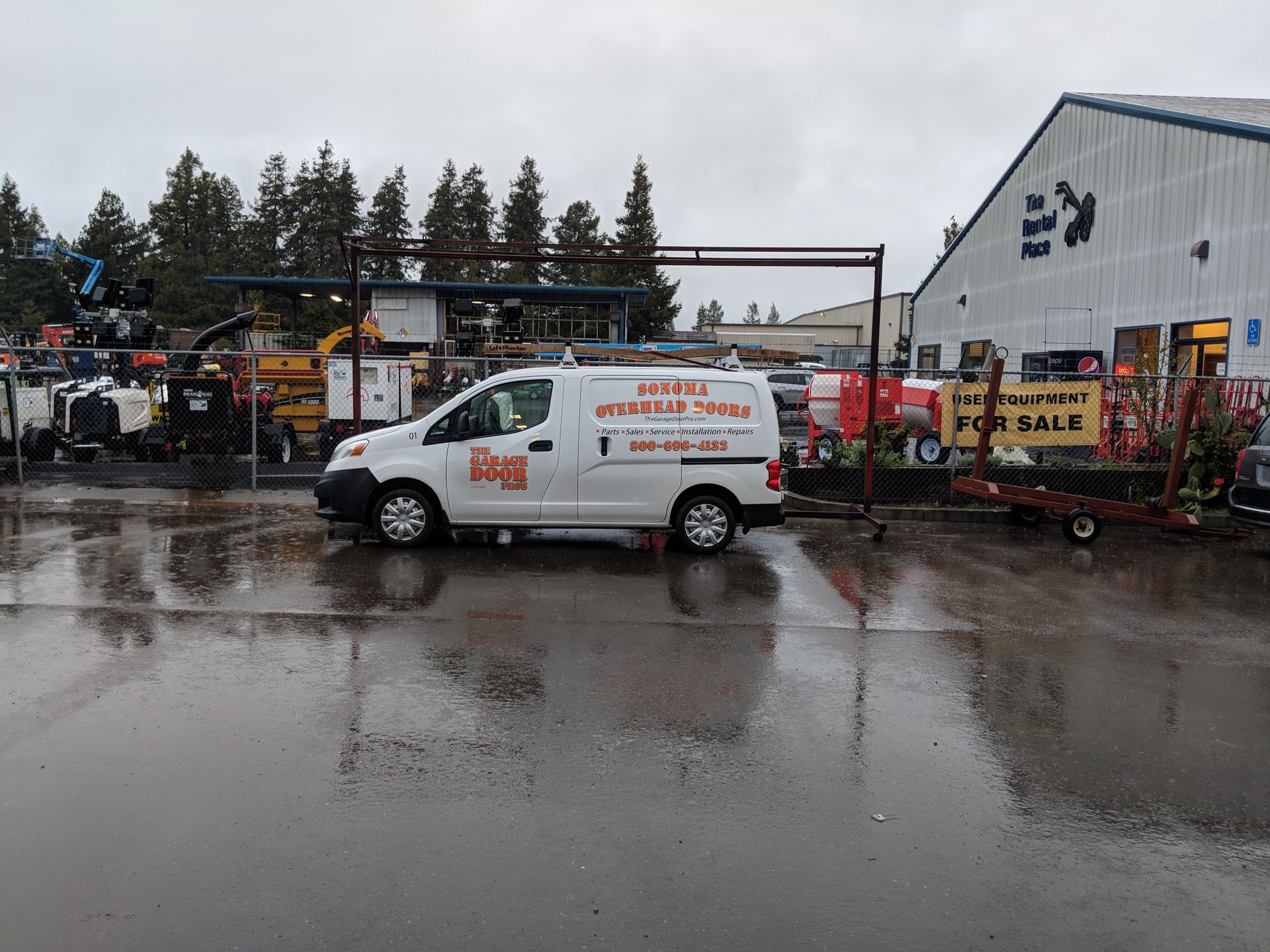 White service van parked outside a wet industrial building on a rainy day