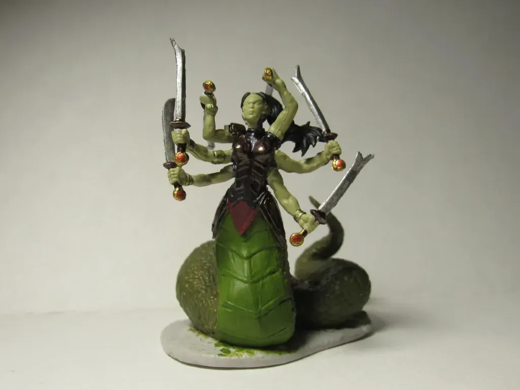 A multi-armed green-skinned Lamia with snake tail wielding swords, on a rocky base.