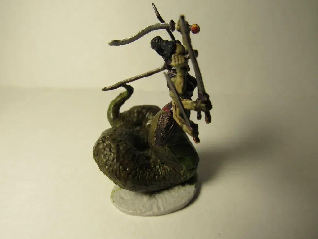 Miniature figure of a snake with a warrior riding it, holding a bow and staff.