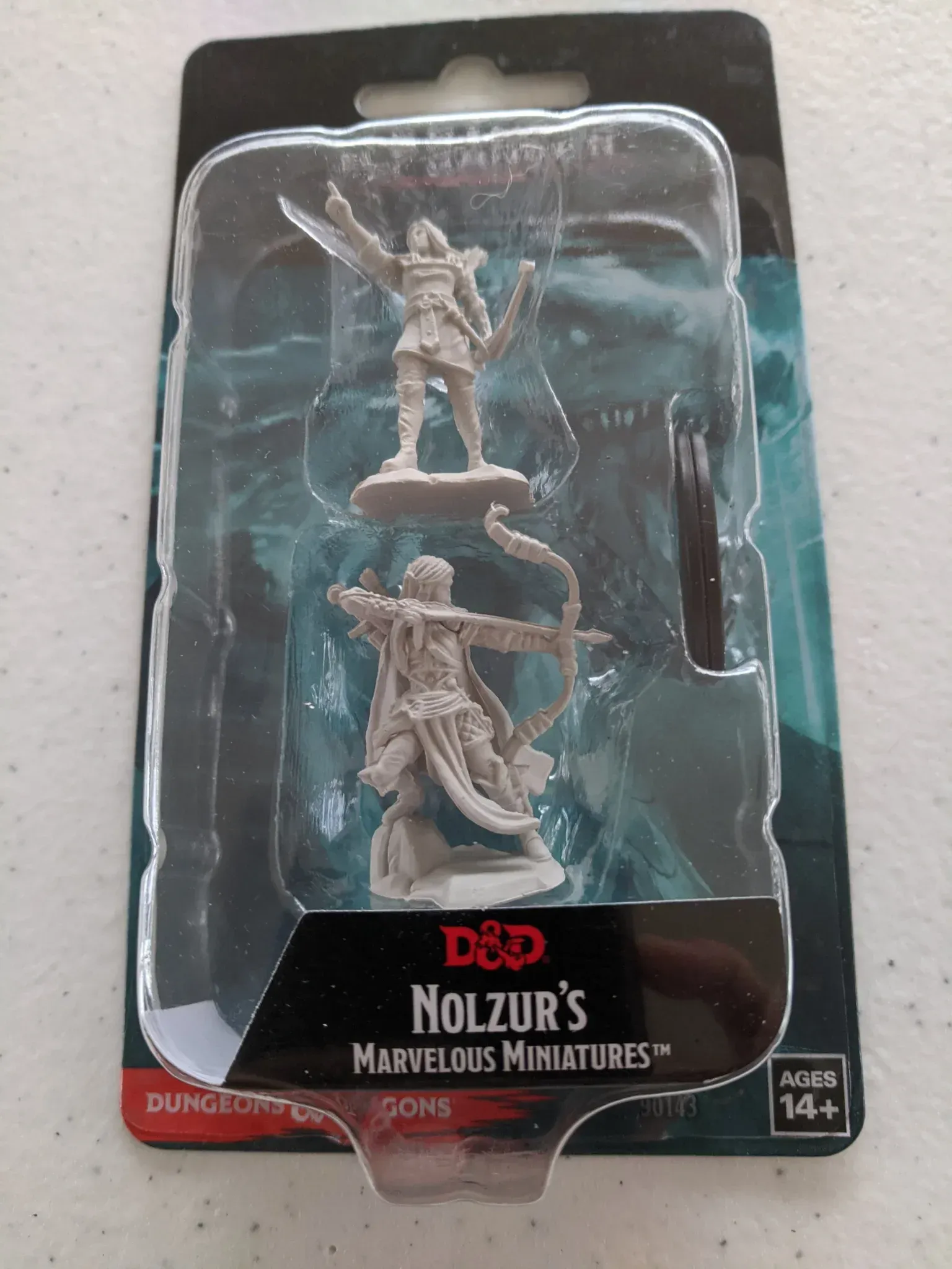 Two D&D miniatures in packaging: one with a sword, the other with a bow, both gray plastic.
