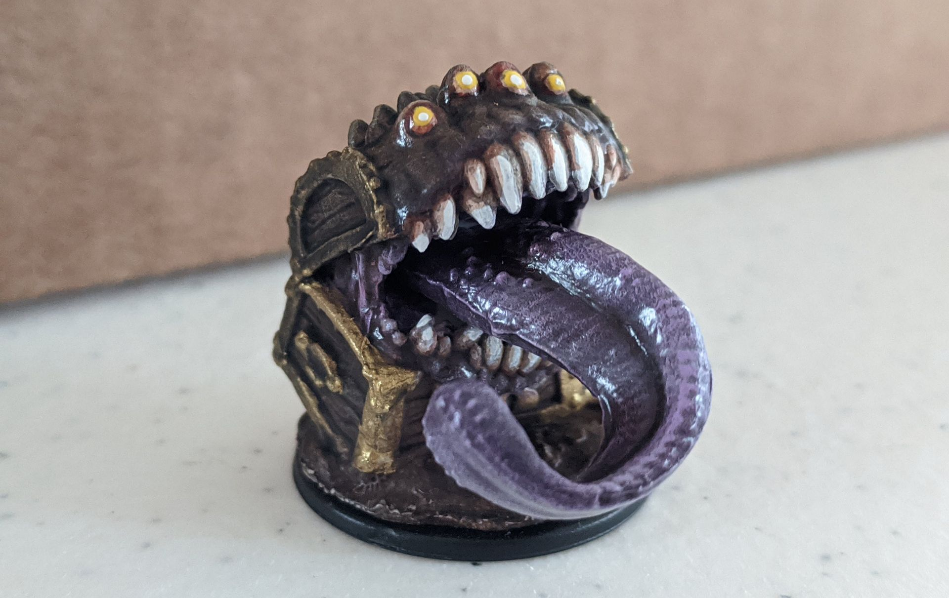 A mimic, a treasure chest with a large mouth and tongue, with sharp teeth, on a black base.