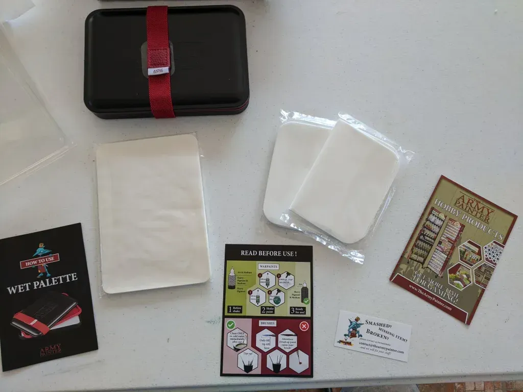 A black case with red strap, game components, including cards and instructions, laid out on a table.