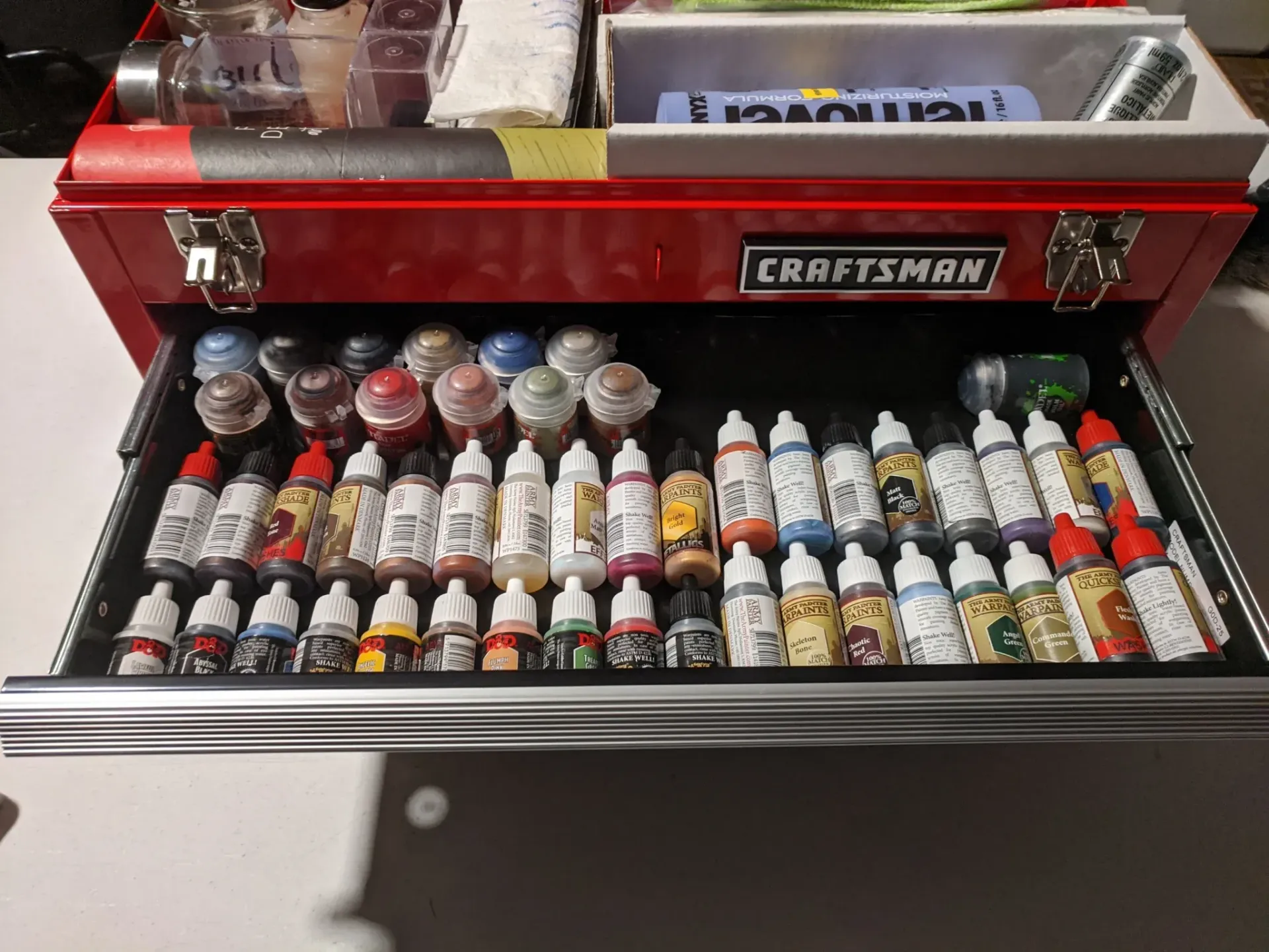 Red Craftsman toolbox drawer open, filled with paint bottles.