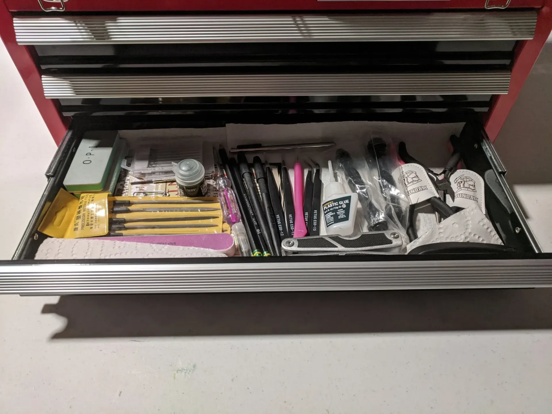 Open red toolbox drawer filled with craft supplies.