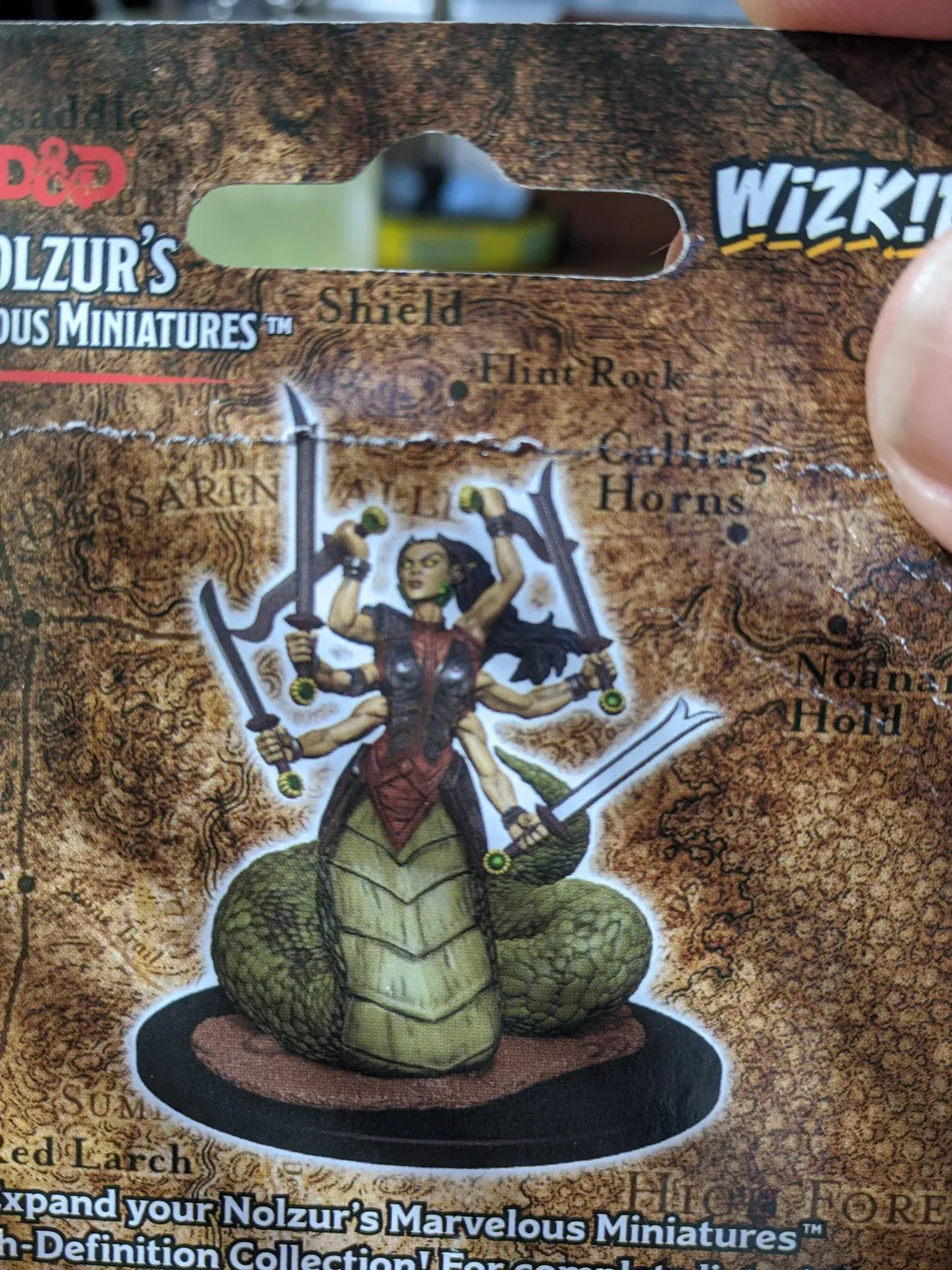 A D&D miniature of a naga, a humanoid with a snake tail and multiple arms wielding swords.