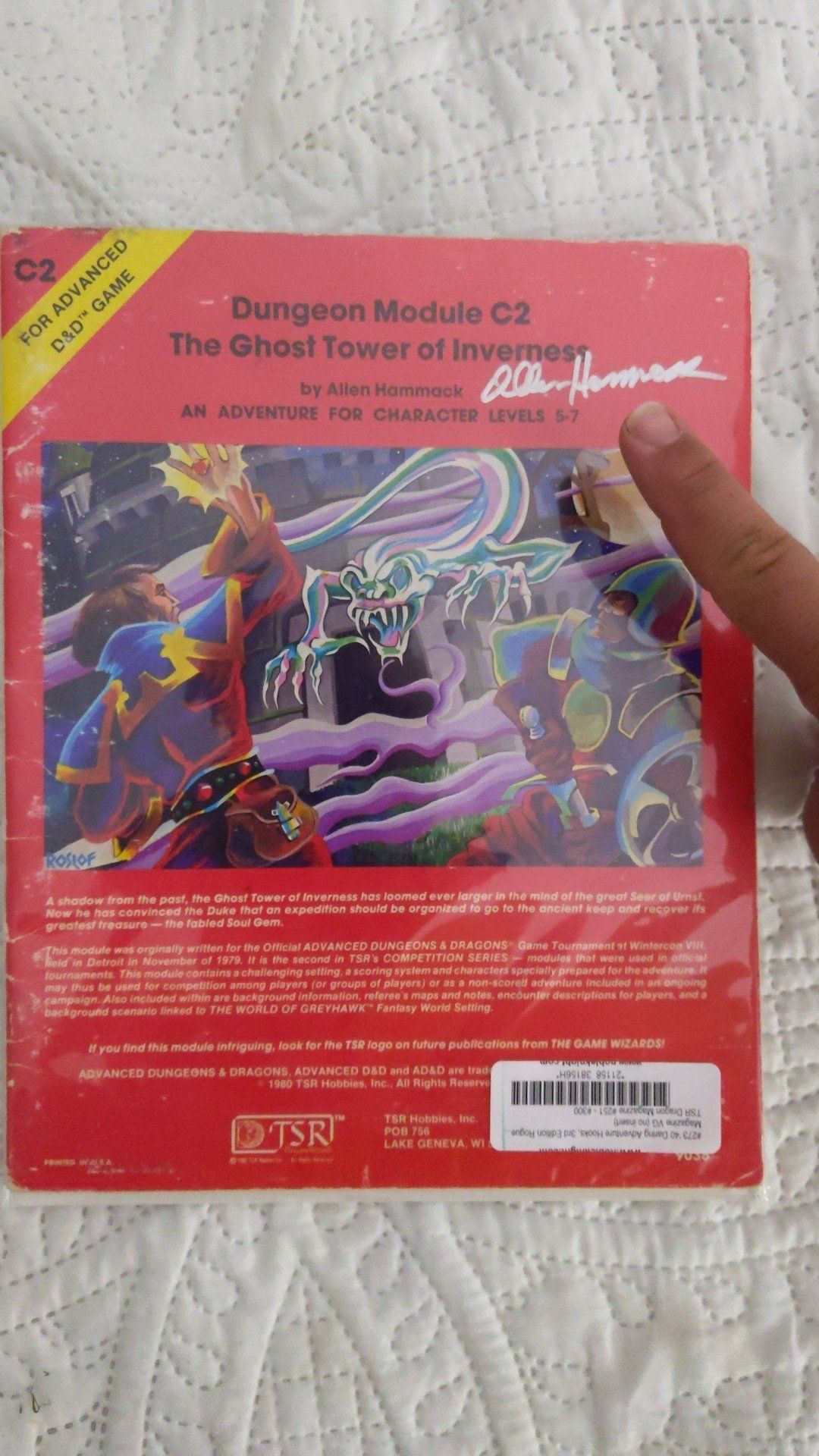 Person pointing at a red Dungeon Module book,