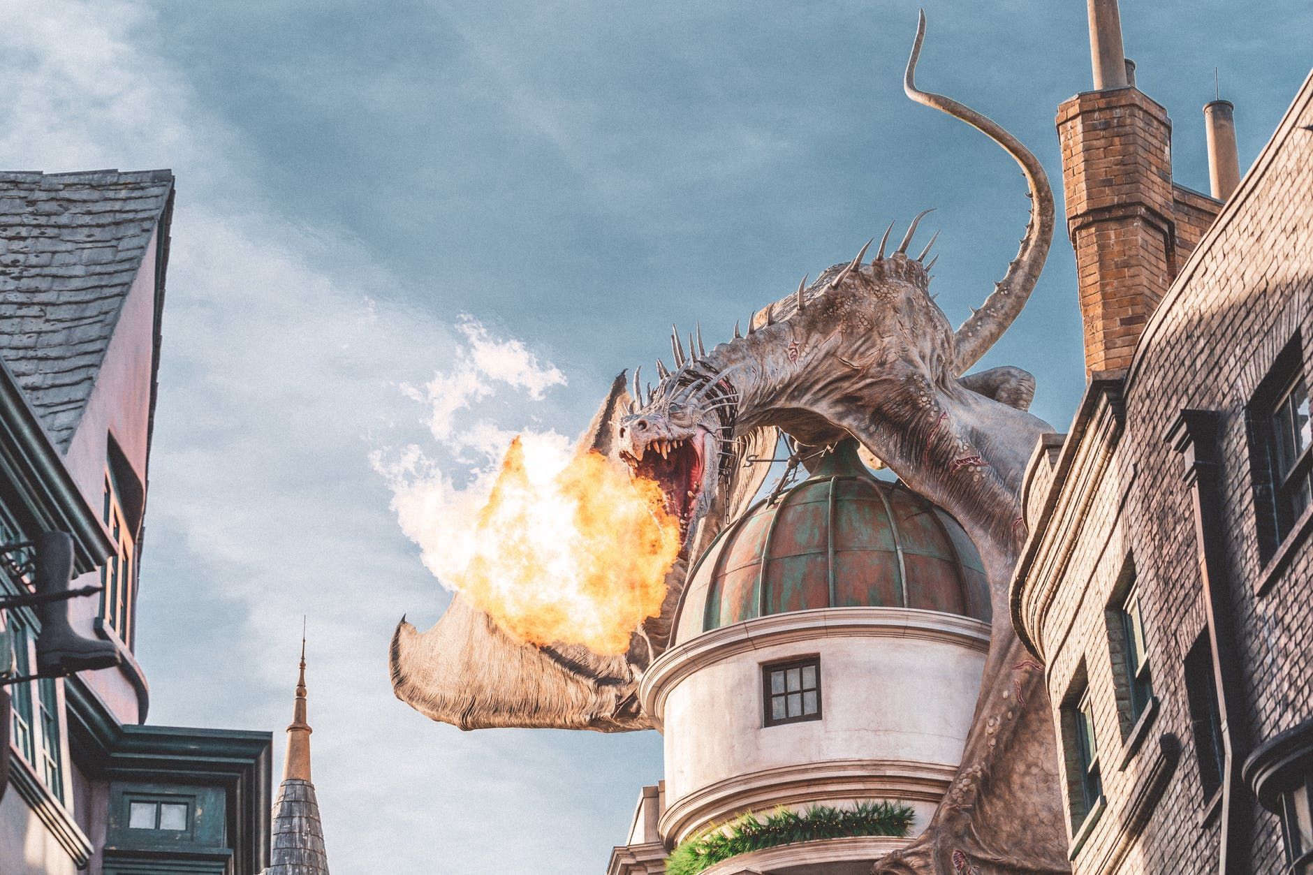 A dragon breathes fire over buildings in a cobblestone street.