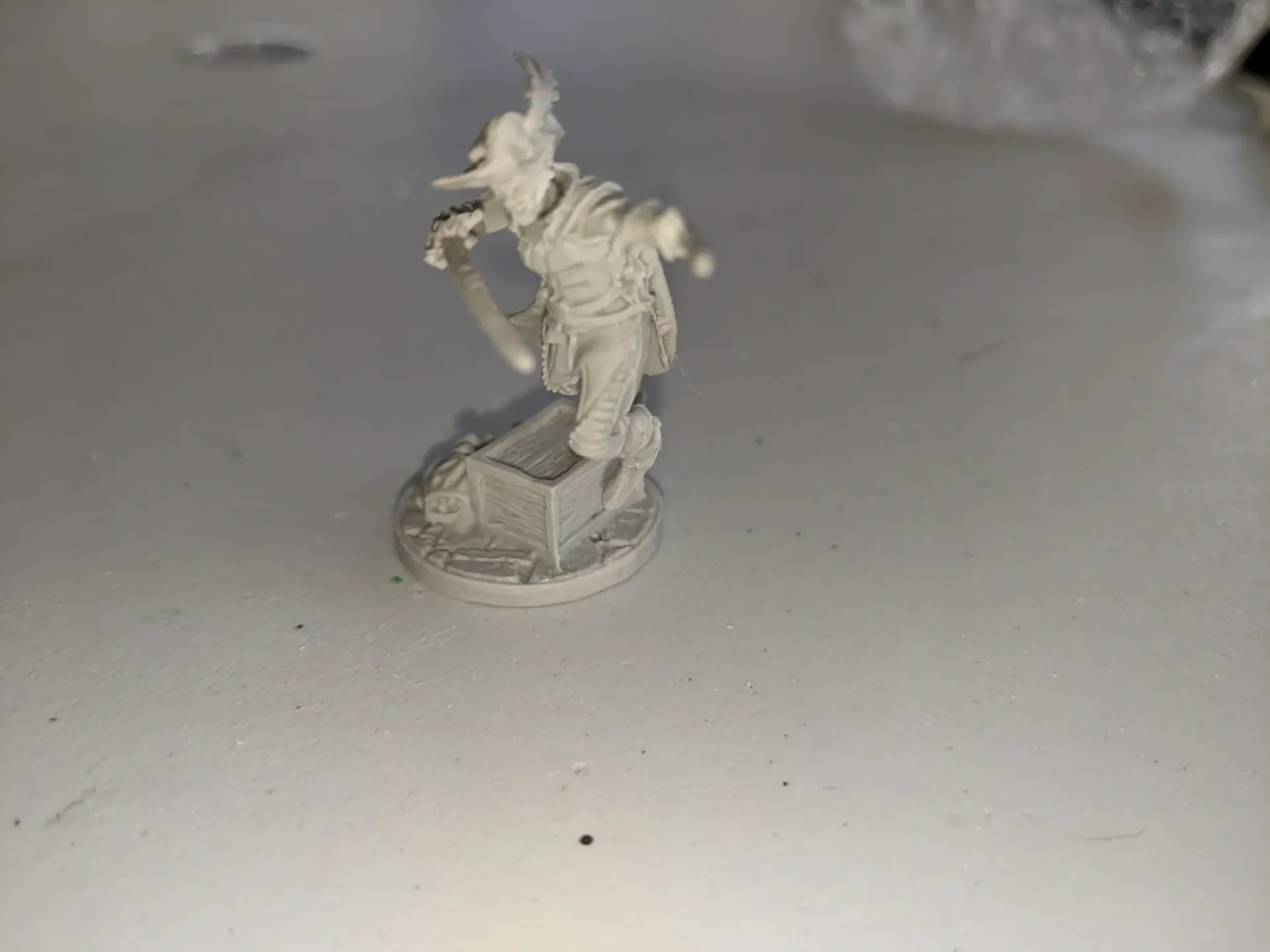 Miniature figure of a pale humanoid, with a sword, standing on a tomb.