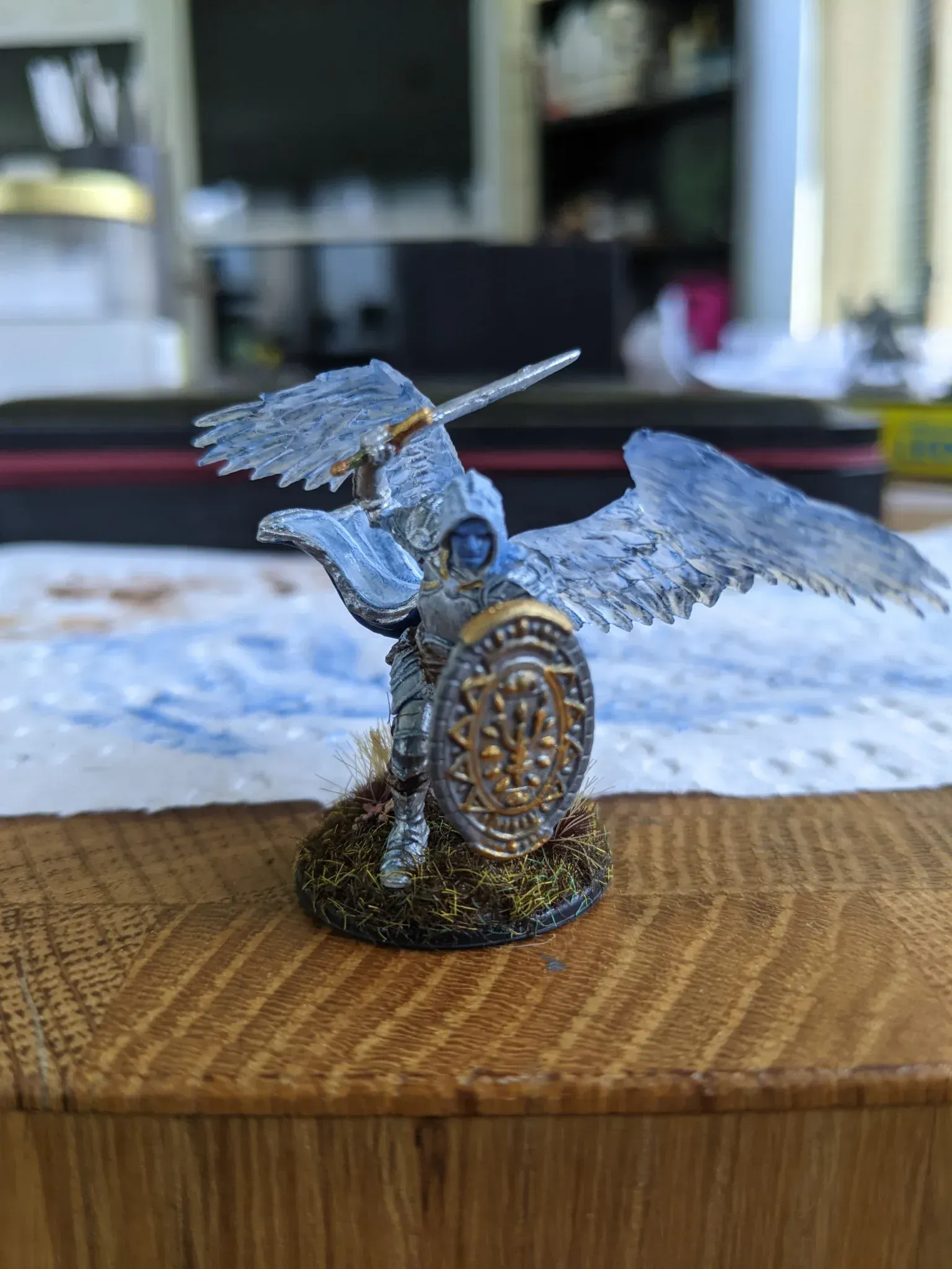 Miniature figure of a winged unicorn warrior in silver and gold armor, holding a shield, standing on a base.