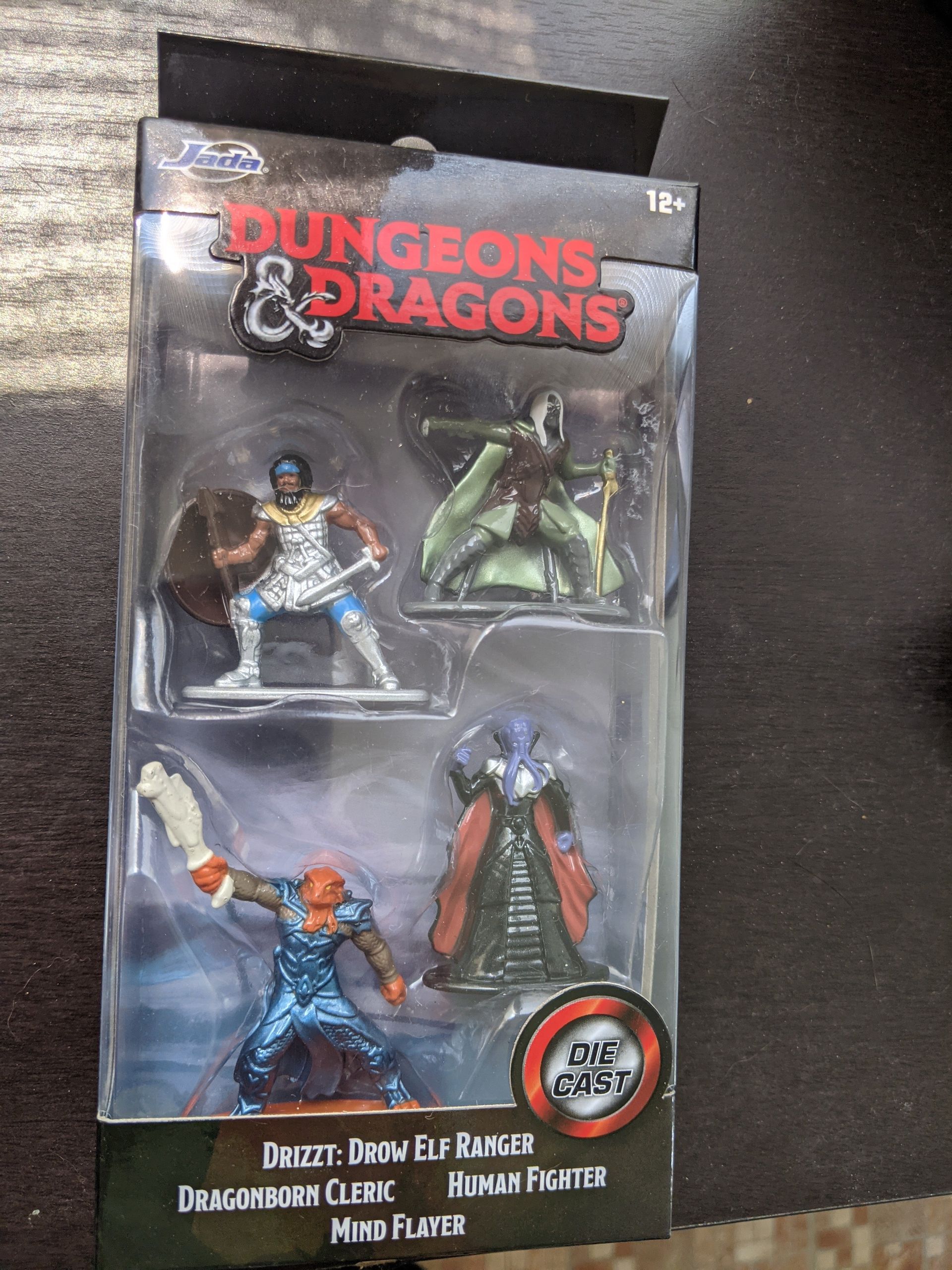 Dungeons & Dragons miniatures set in a clear package: Orc, Elf, Human, and Dragonborn figures.