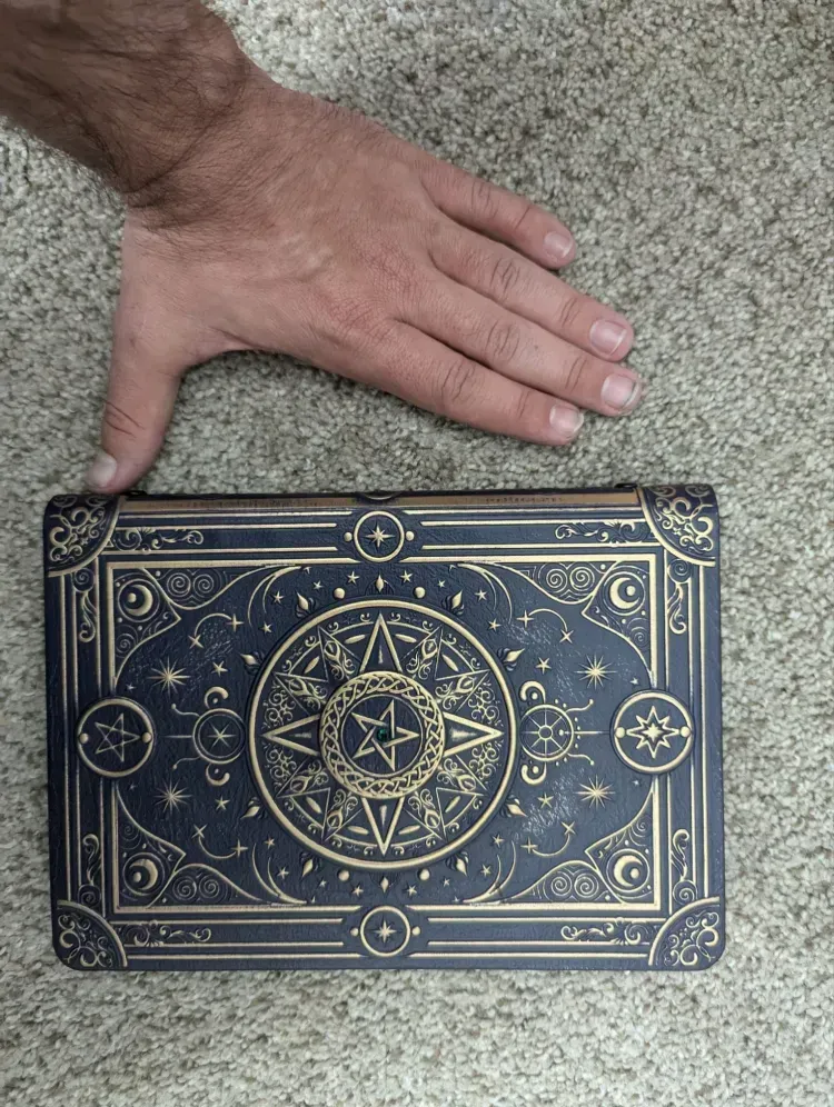 A person is holding a book with a pentagram on it.