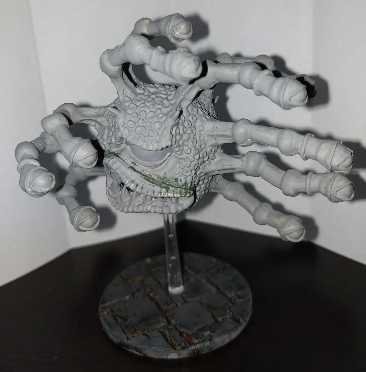 Gray, monstrous creature with multiple tentacle-like arms, mounted on a base.