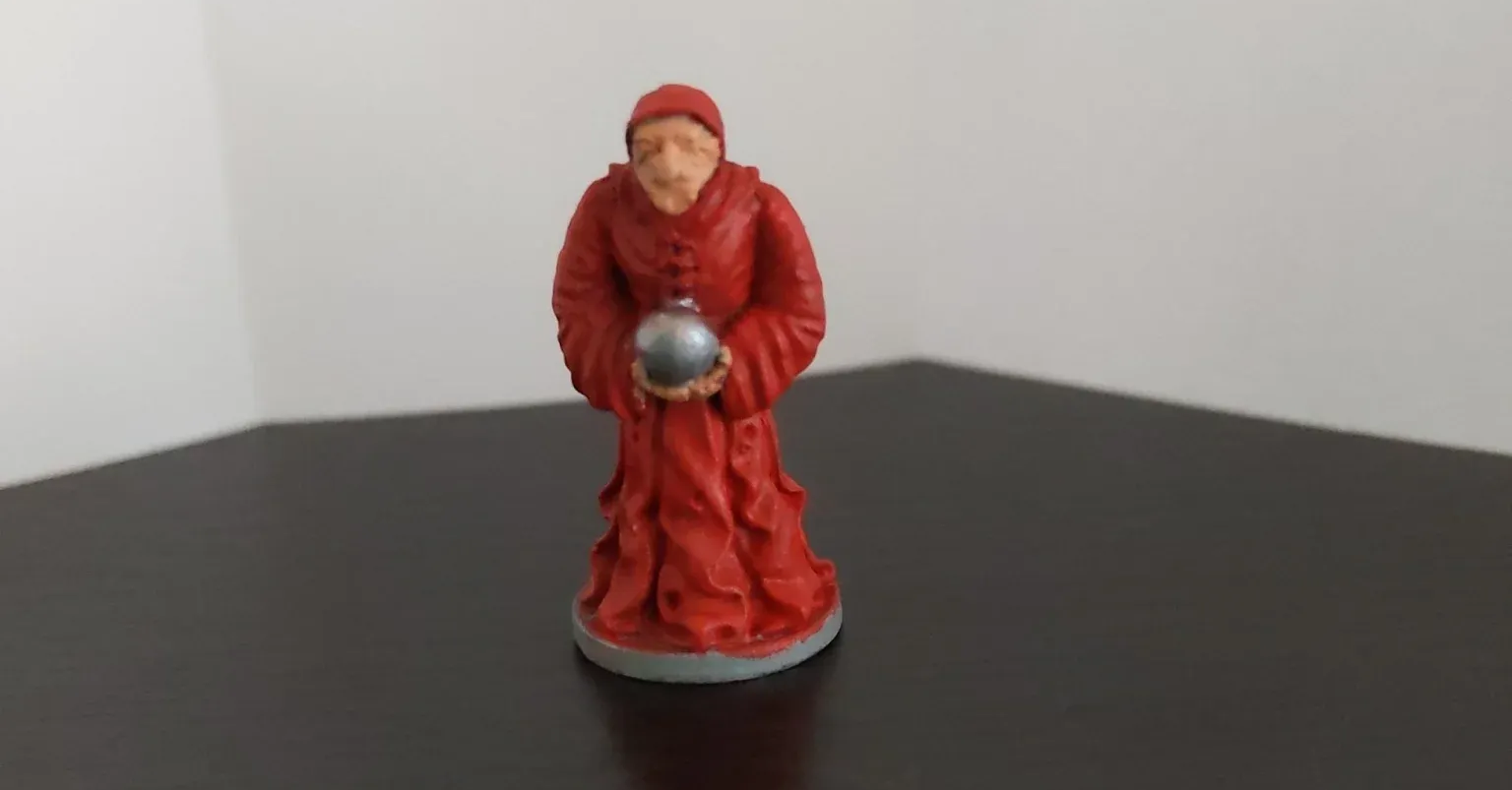 Miniature of a robed figure holding a silver orb, with red clothing and a dark surface background.