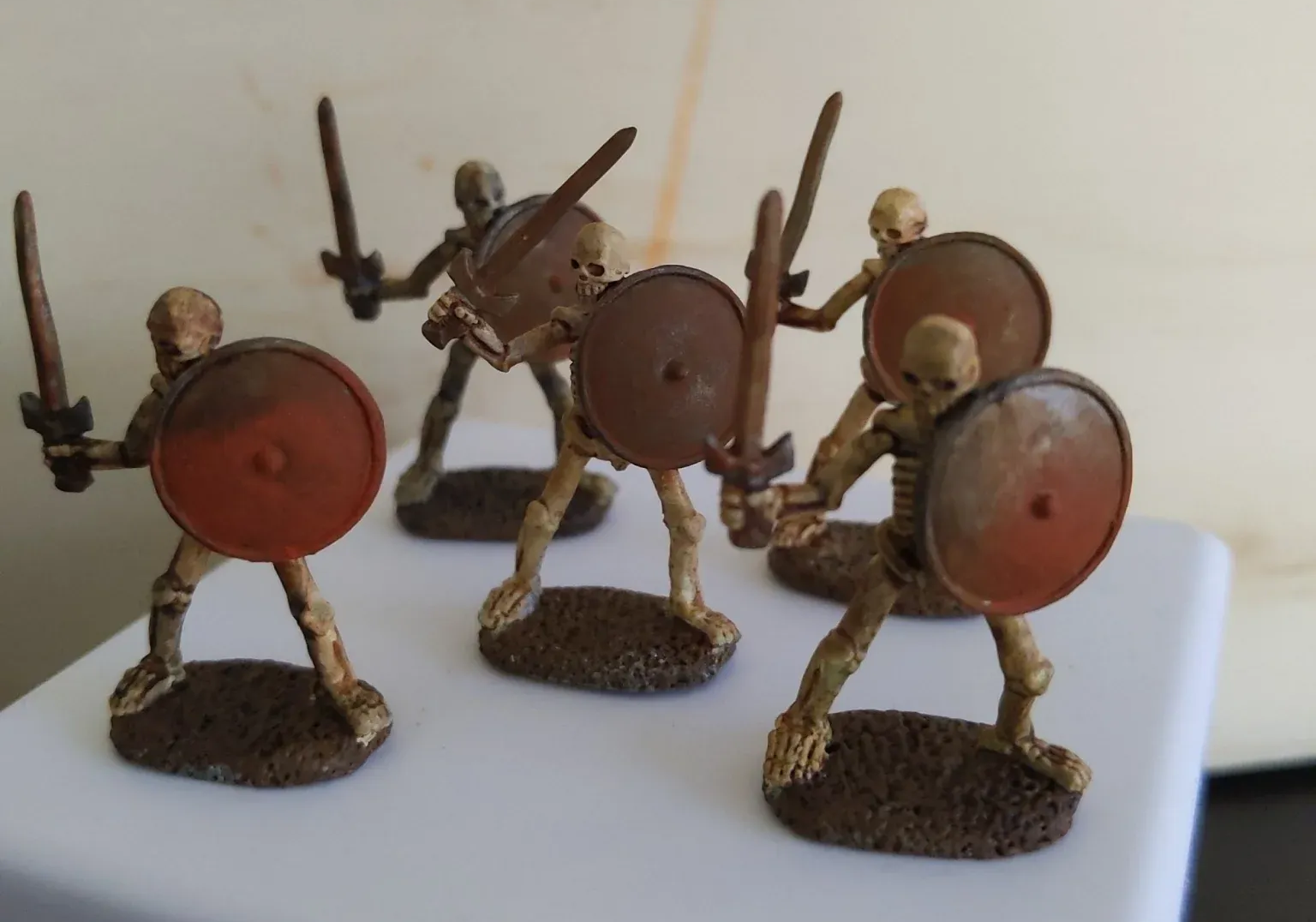 Six miniature painted skeleton figures with swords and shields, posed on bases.