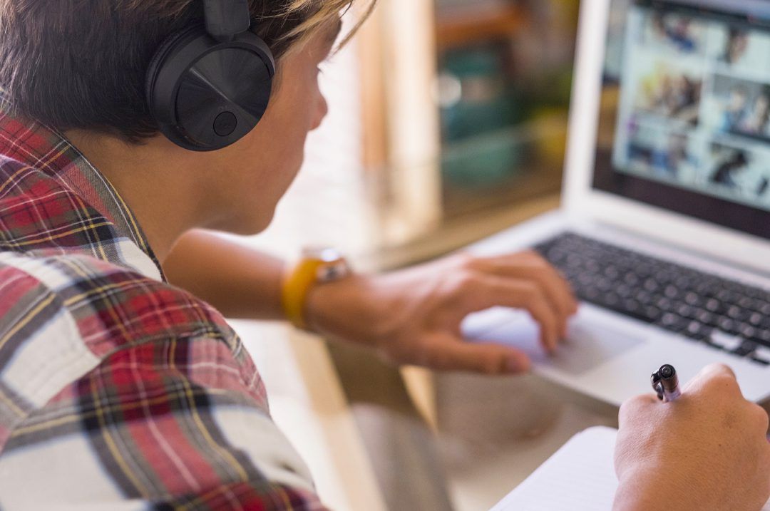 A man wearing headphones is using a laptop computer.